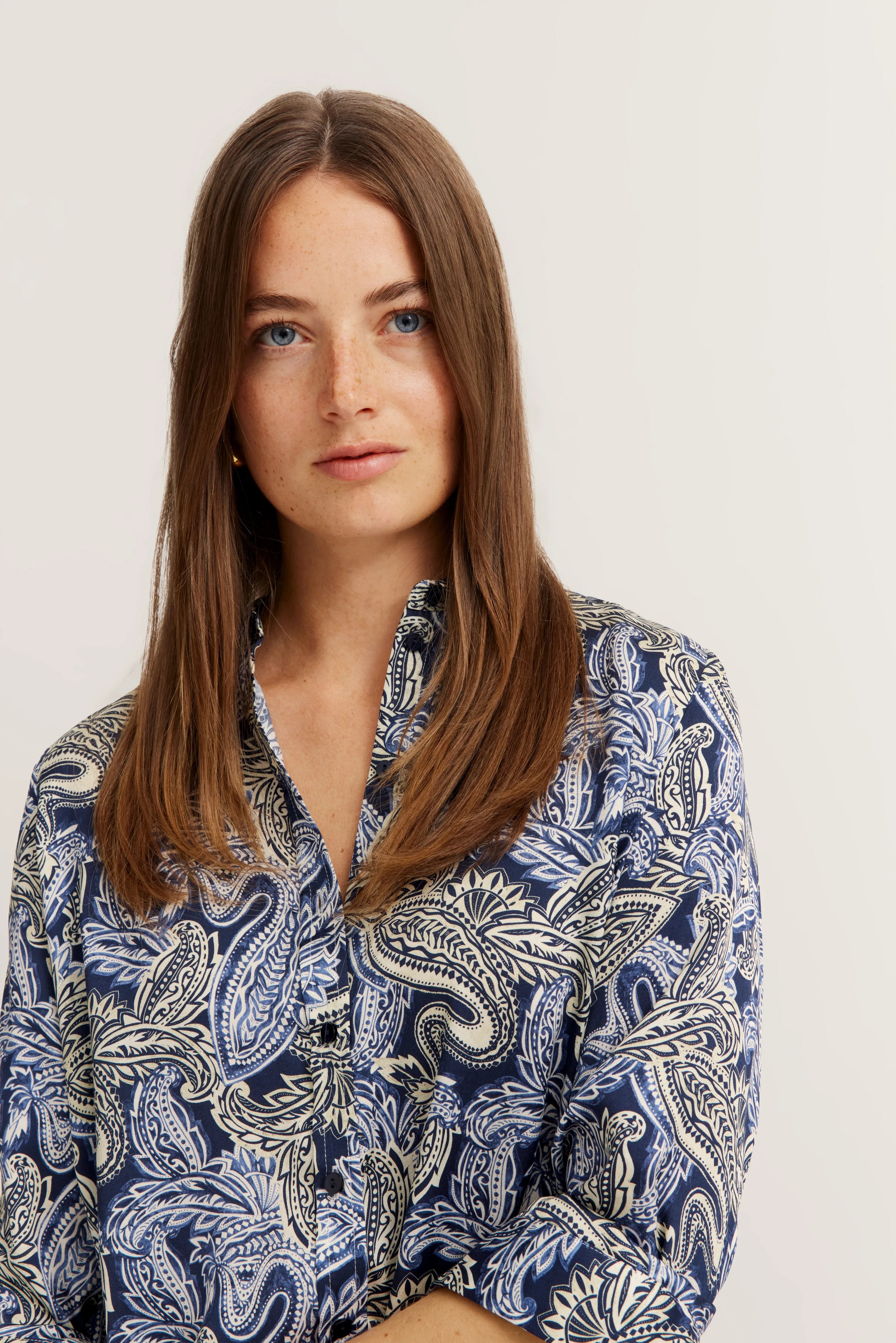 Damenbluse mit blau-weißem Paisleymuster, Model halbnah, entspanntes Posing.