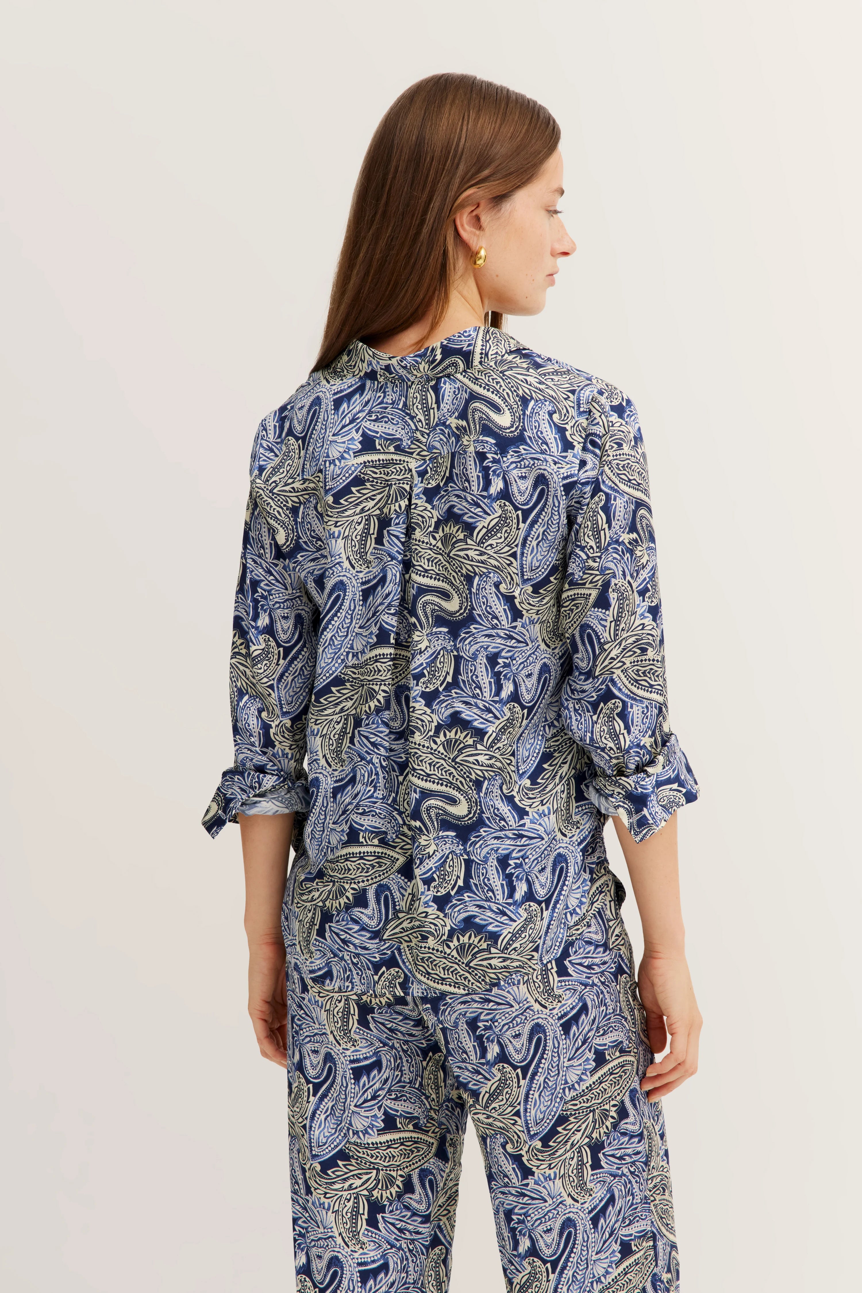 Model in blauem Paisley-Muster-Outfit von bugatti, Rückansicht, entspanntes Posing.