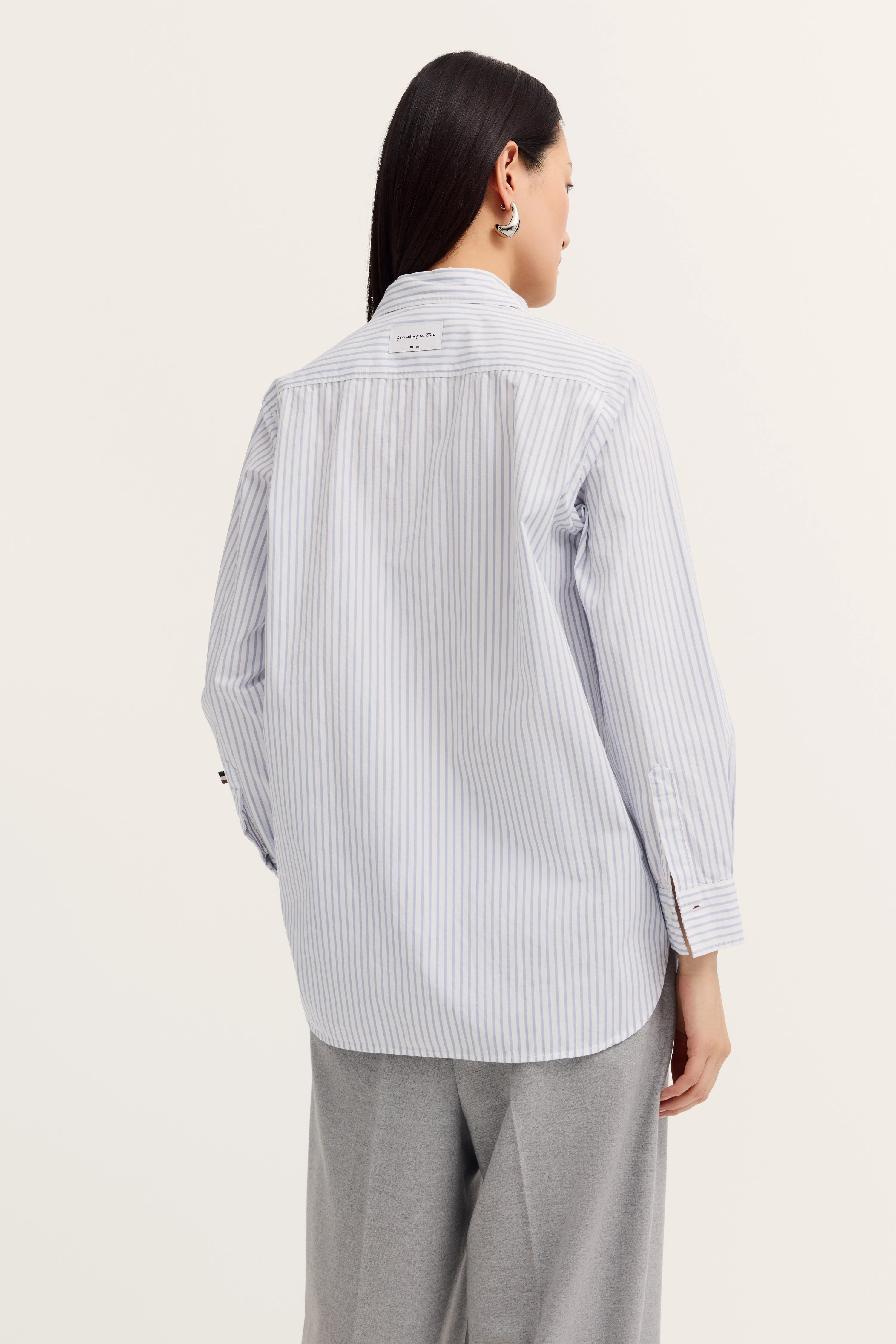 Streifenhemd in Blau-Weiß, locker geschnitten, mit grauer Hose, Model von hinten.
