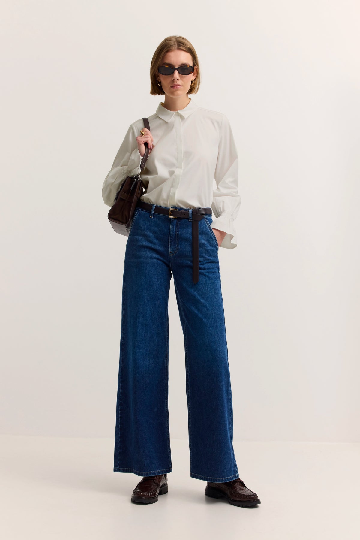 Weißes Hemd, blaue Jeans, Modelbild, entspannte Haltung, bugatti Stil.