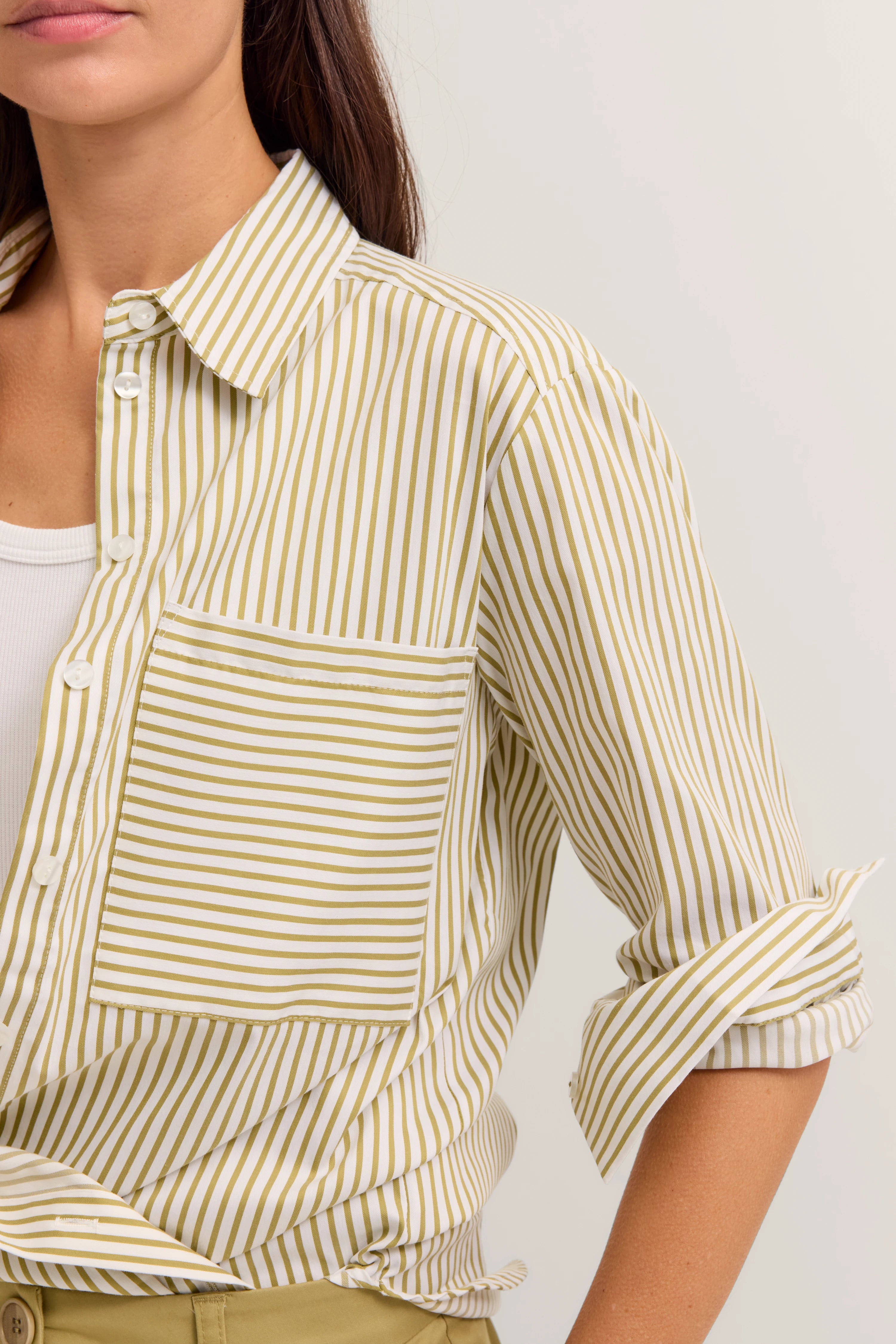 Gestreifte Bluse in Beige-Weiß auf Model, Ärmel hochgekrempelt, lässiger Look.