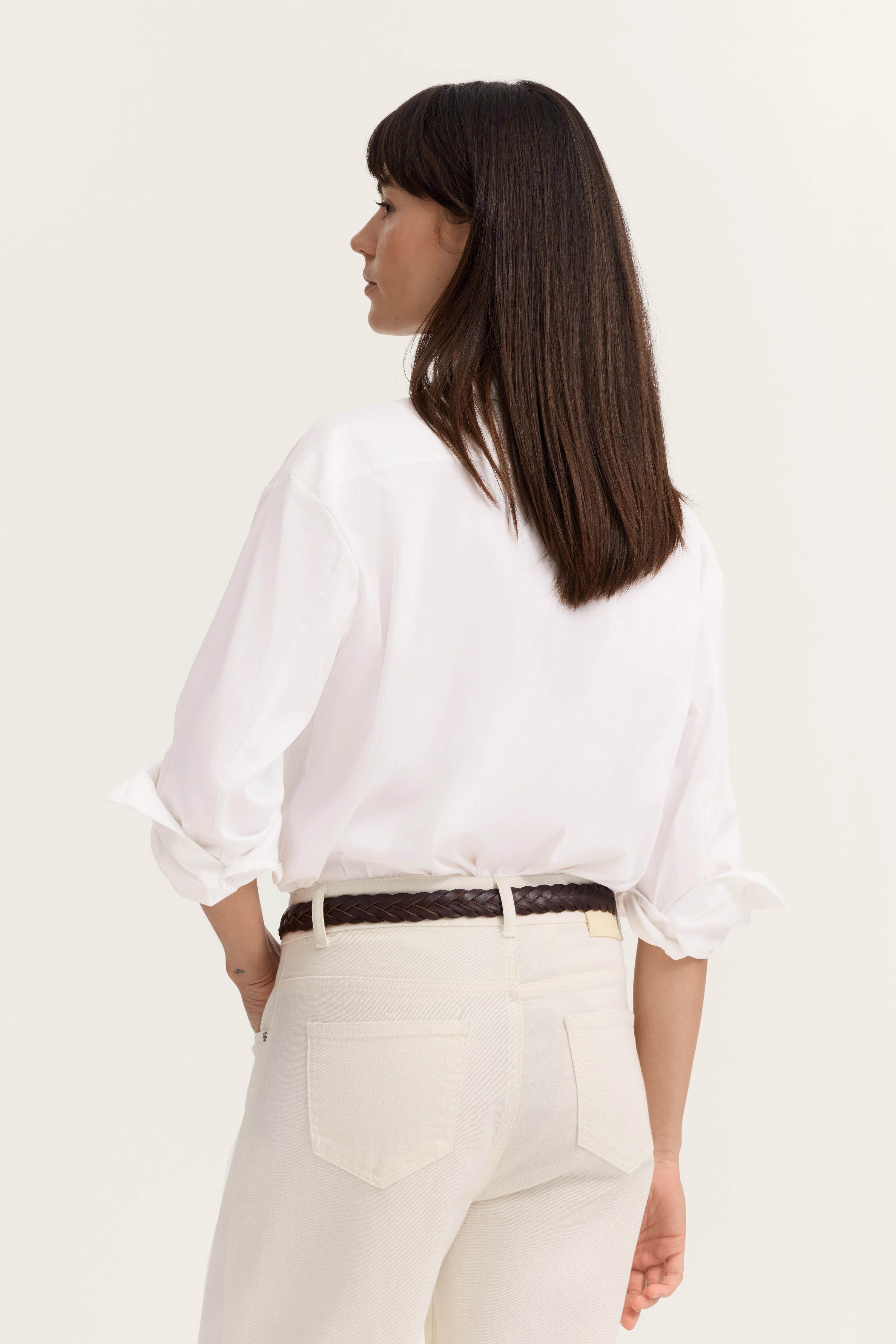 Weiße Bluse und cremefarbene Hose, Model von hinten, entspanntes Posing, bugatti Stil.