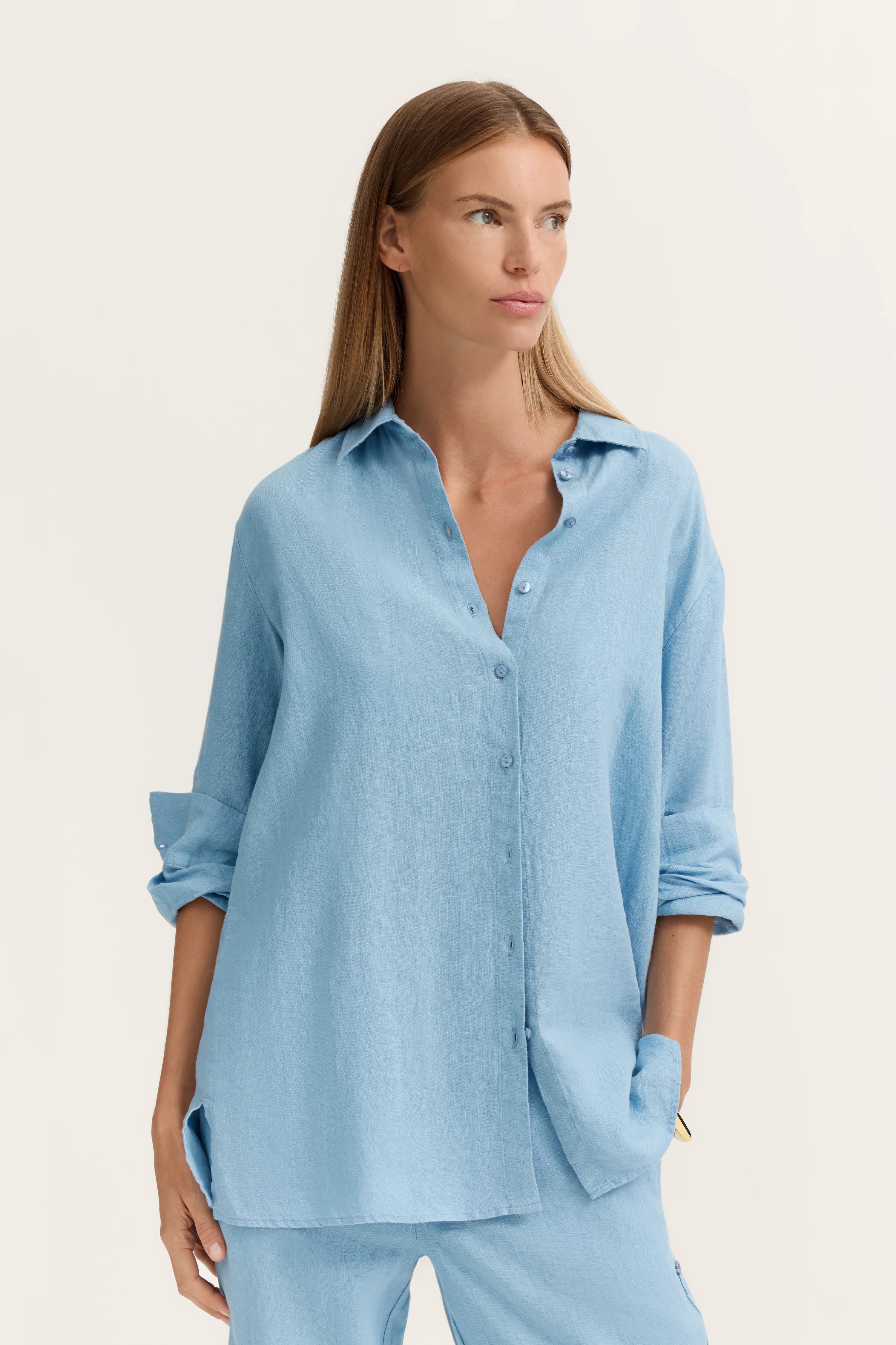 Elegantes Modelbild mit hellblauer lockerer Bluse und passender Hose, entspannte Pose.