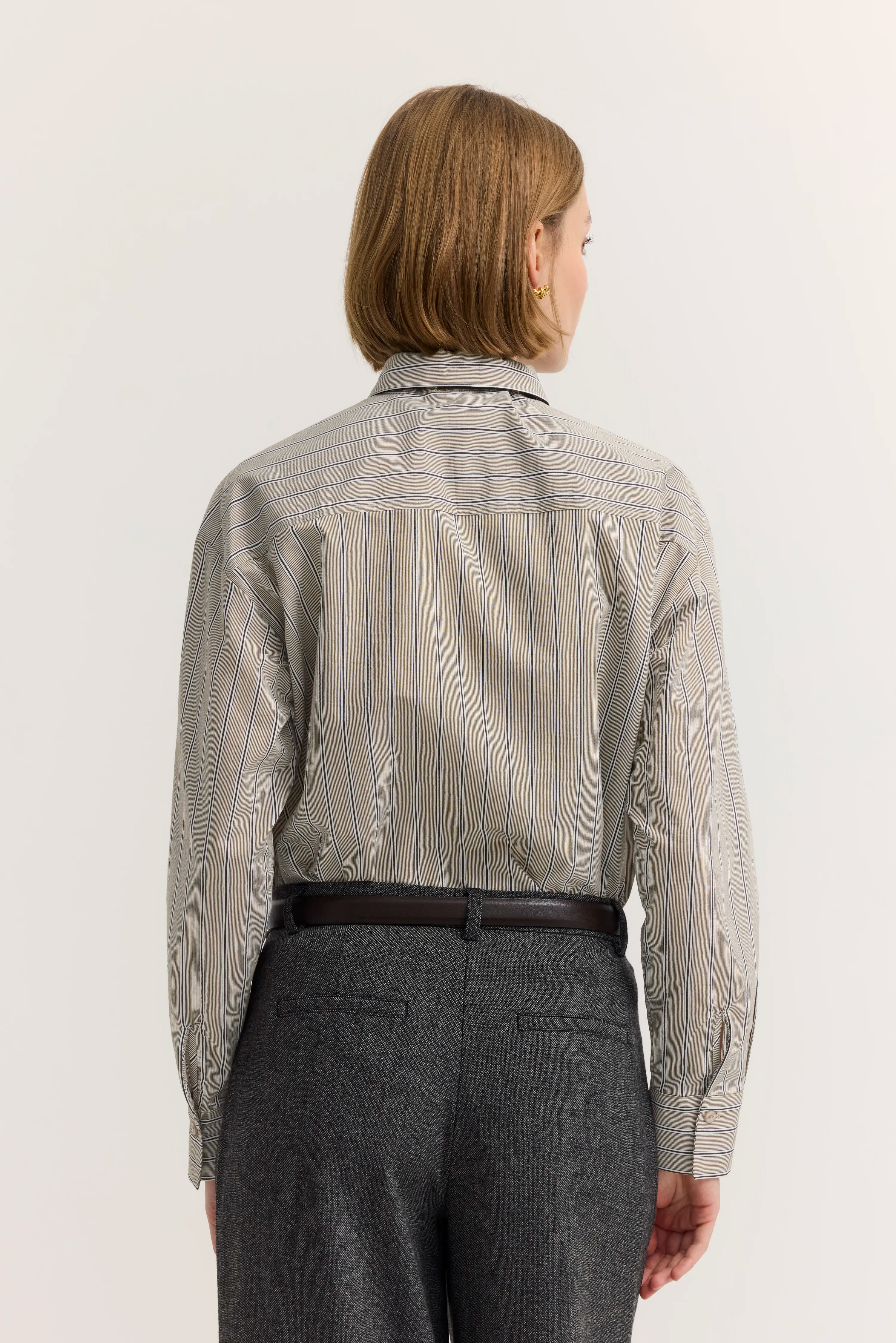 Gestreiftes Hemd in Grautönen, Rückansicht, kombiniert mit grauer Hose, legeres Modelbild.