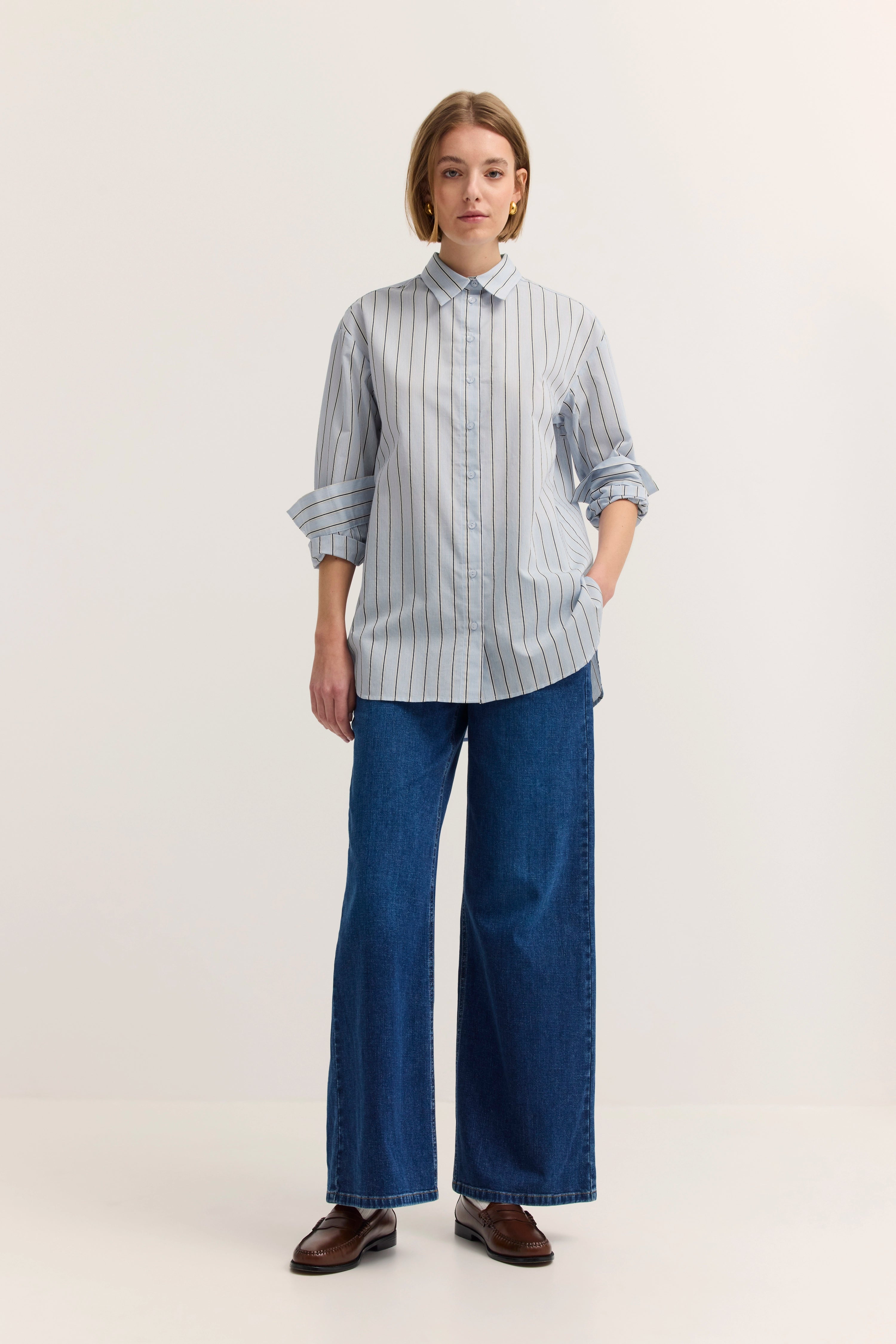 Gestreiftes Hemd in Blau-Weiß mit blauen Jeans, Modelbild, entspannte Pose.