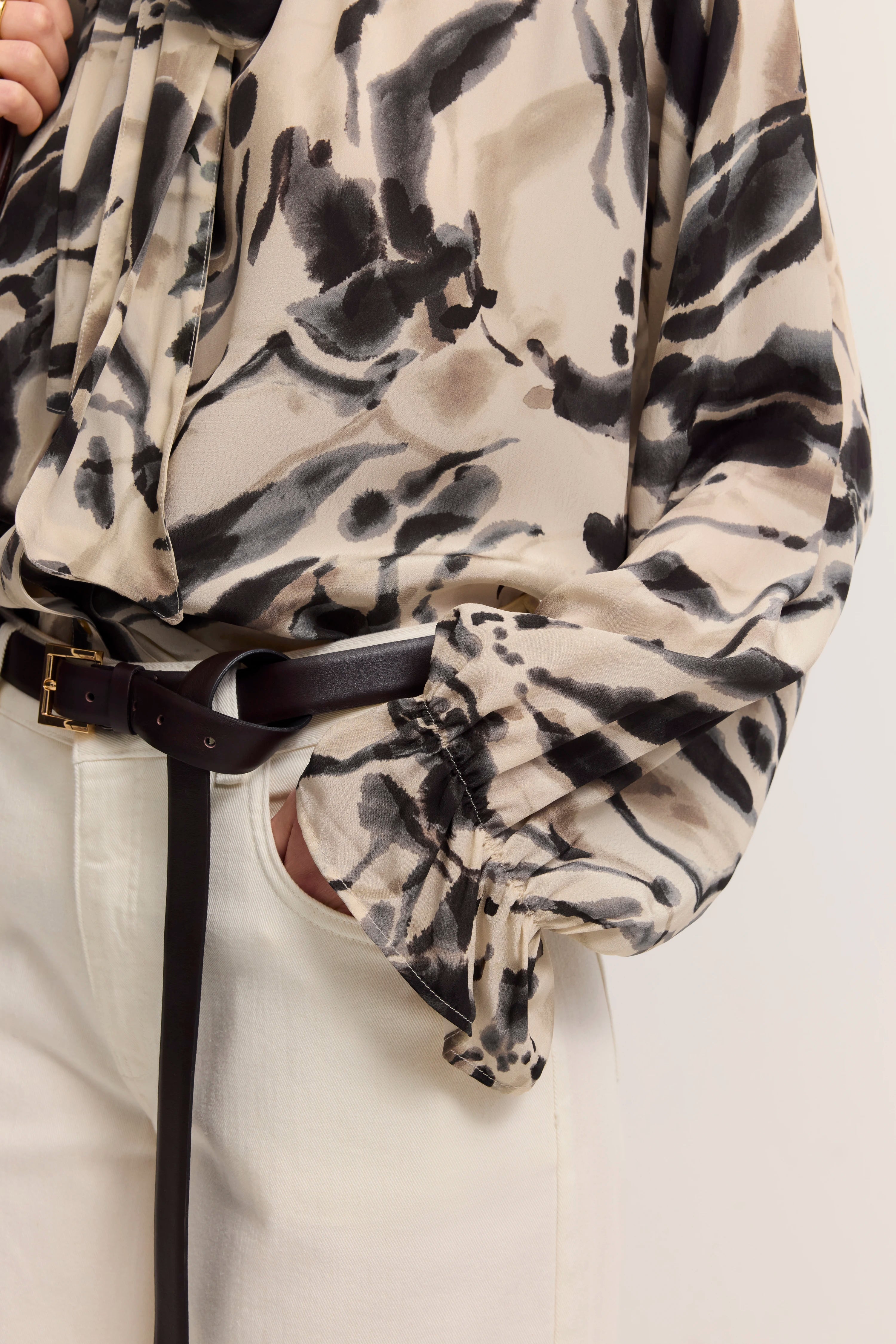 Bluse mit abstraktem Print in Beige und Schwarz, kombiniert mit weißer Hose