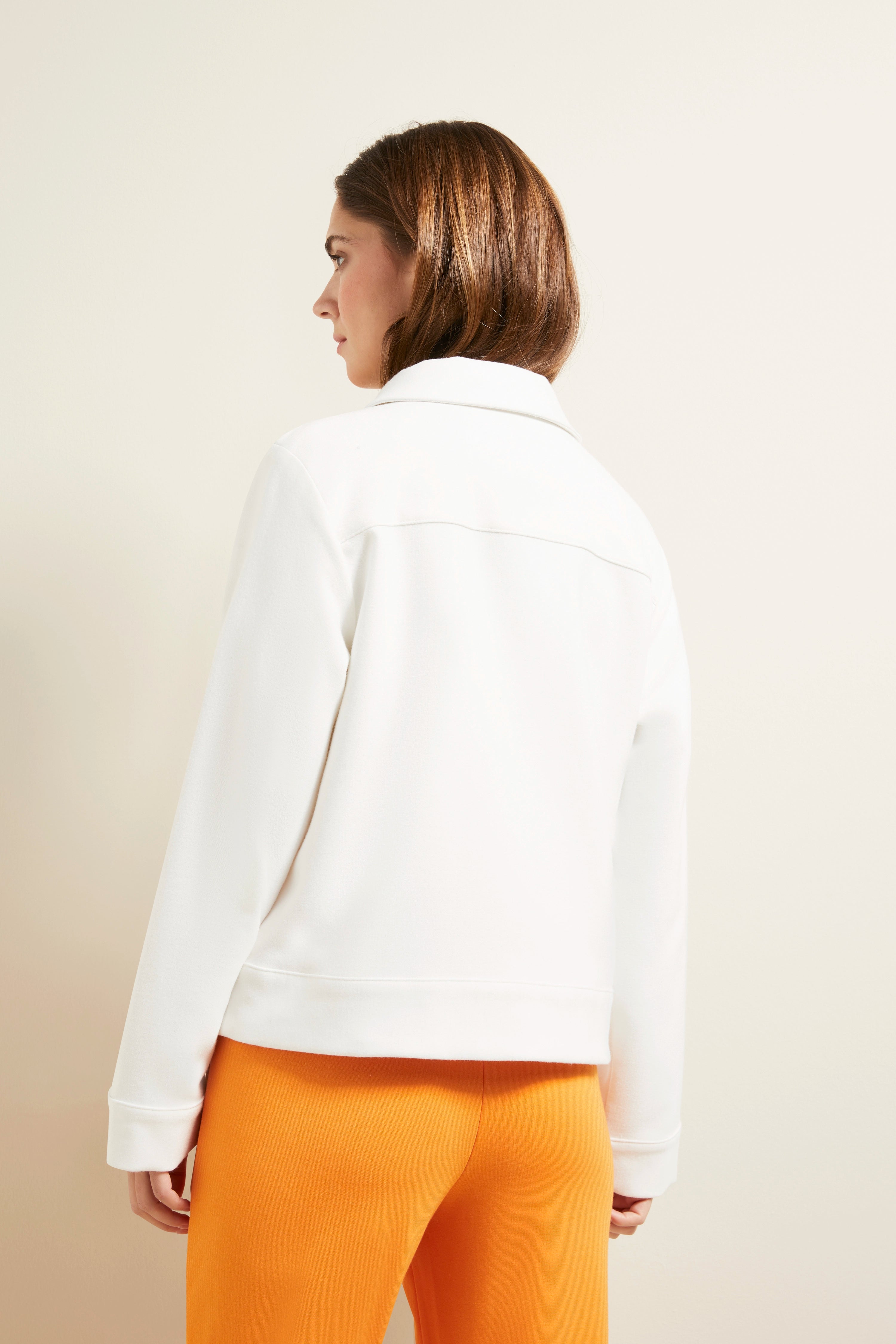 Weiße Jacke, orange Hose, Model von hinten, entspannte Pose, bugatti Stil.