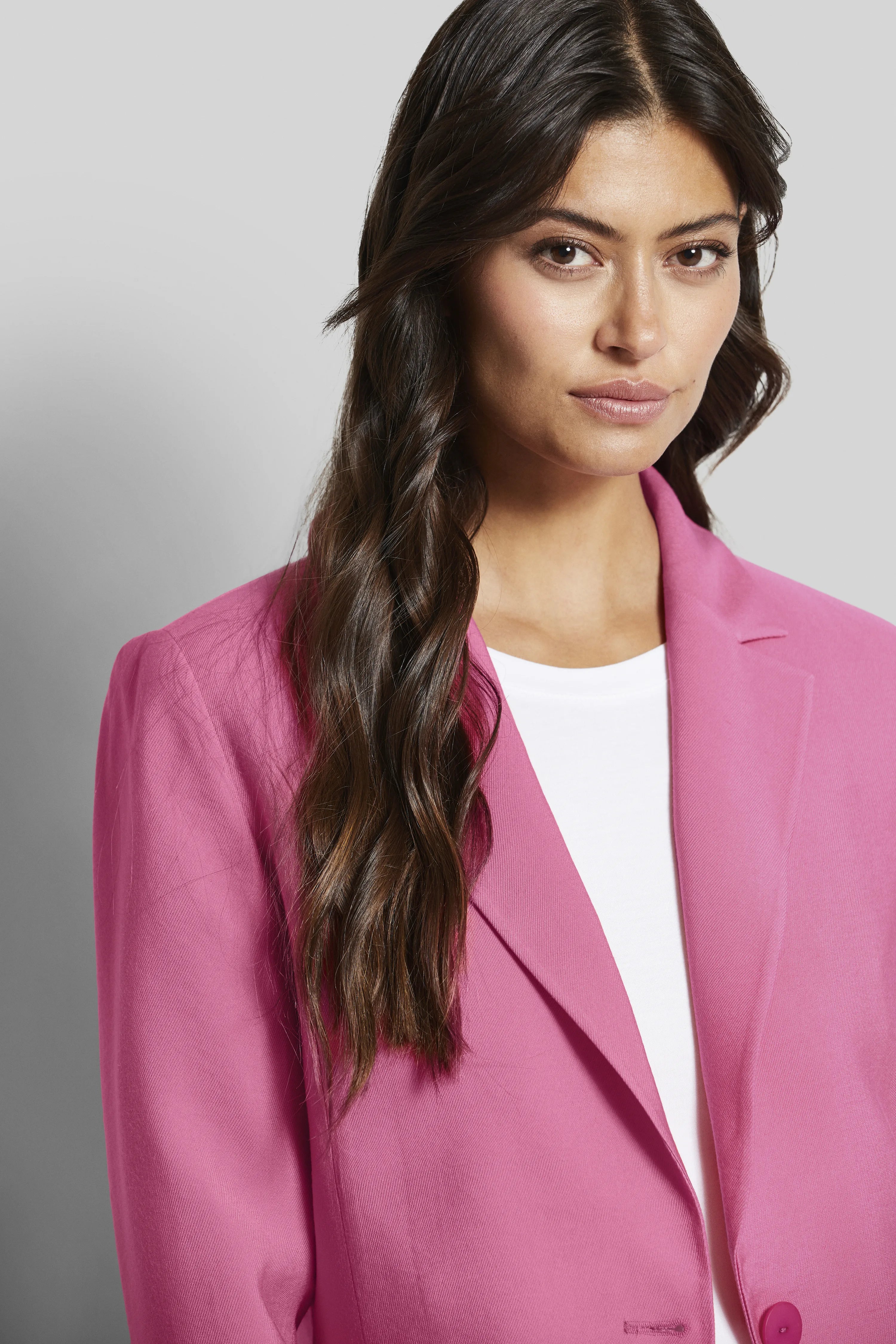 Model in pink bugatti blazer, white shirt, half-profile, elegant and stylish.
