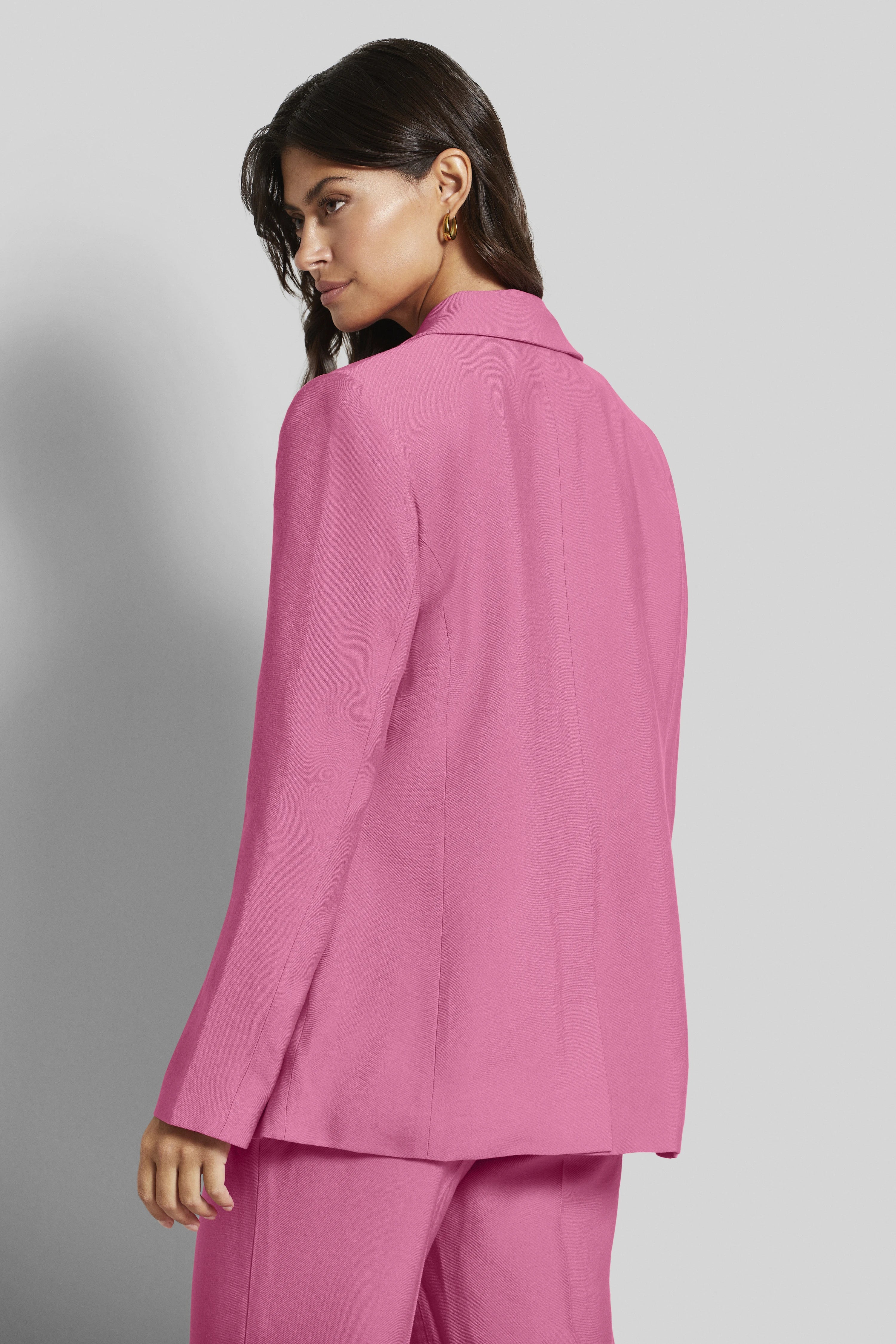 Vrouw in roze pak, rugaanzicht, model draait hoofd opzij.