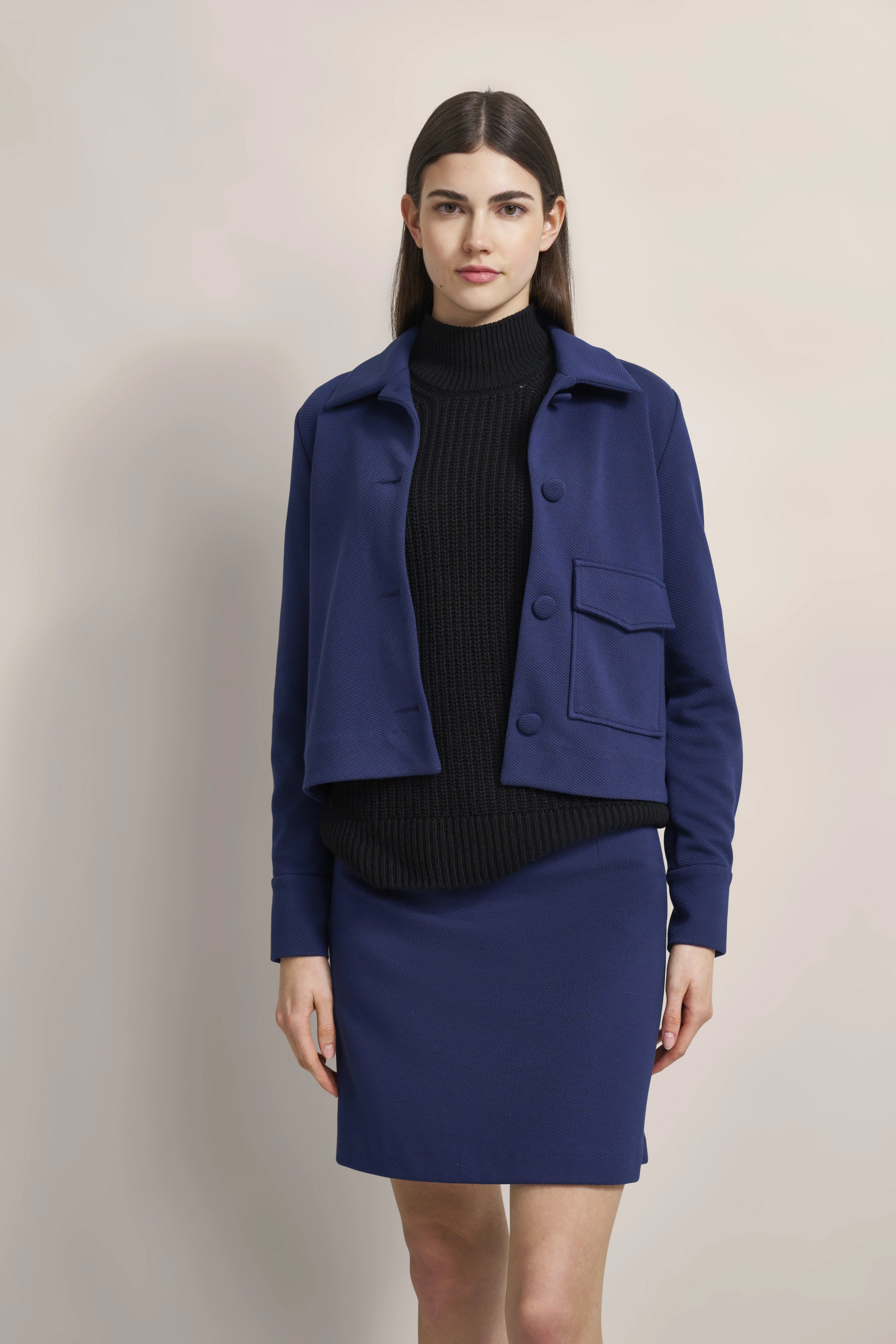 Modell in blauem bugatti-Blazer und Rock, schwarzer Rollkragen. Elegante, entspannte Pose.