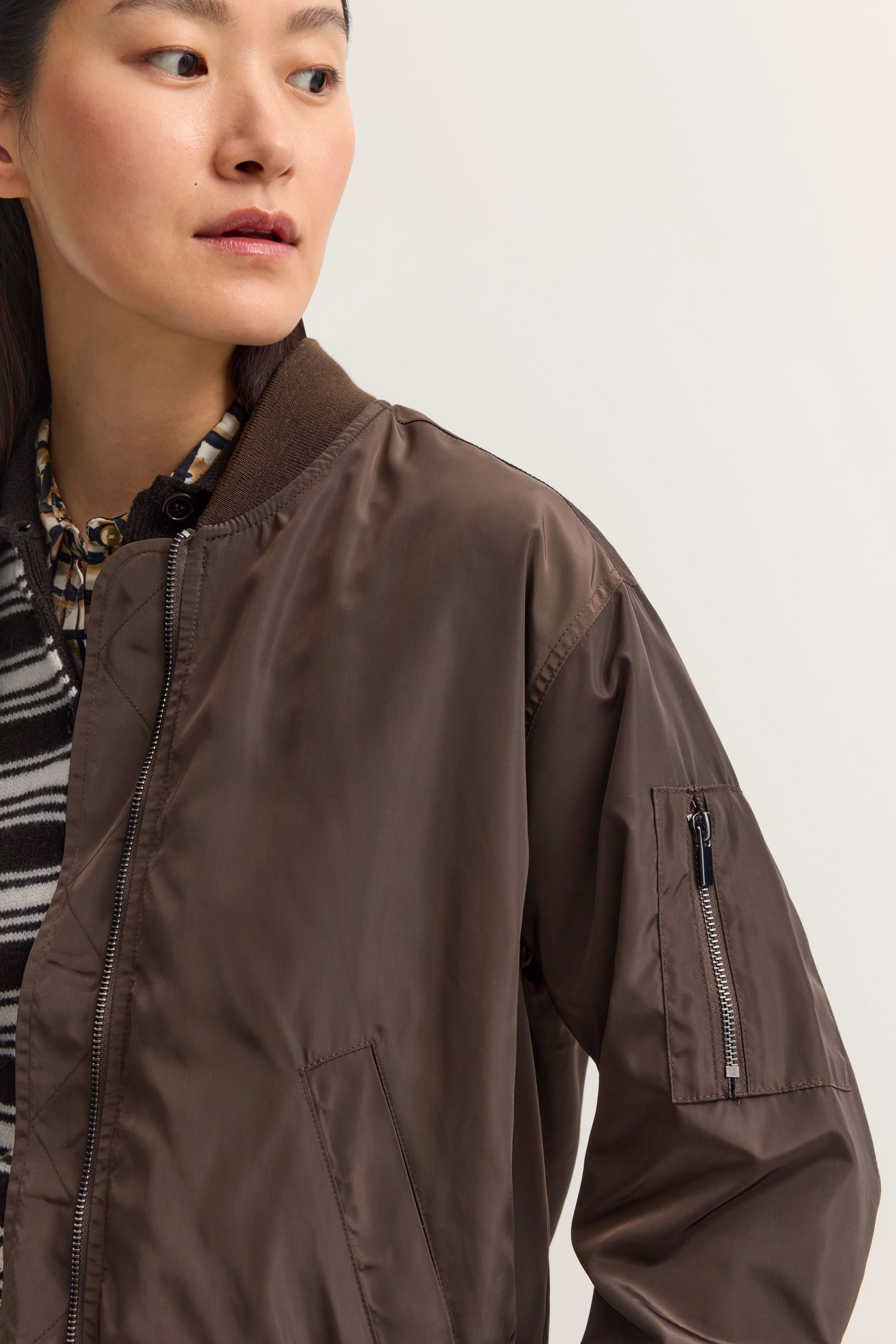 Braune bugatti Bomberjacke mit Musterhemd, Model im Halbprofil.