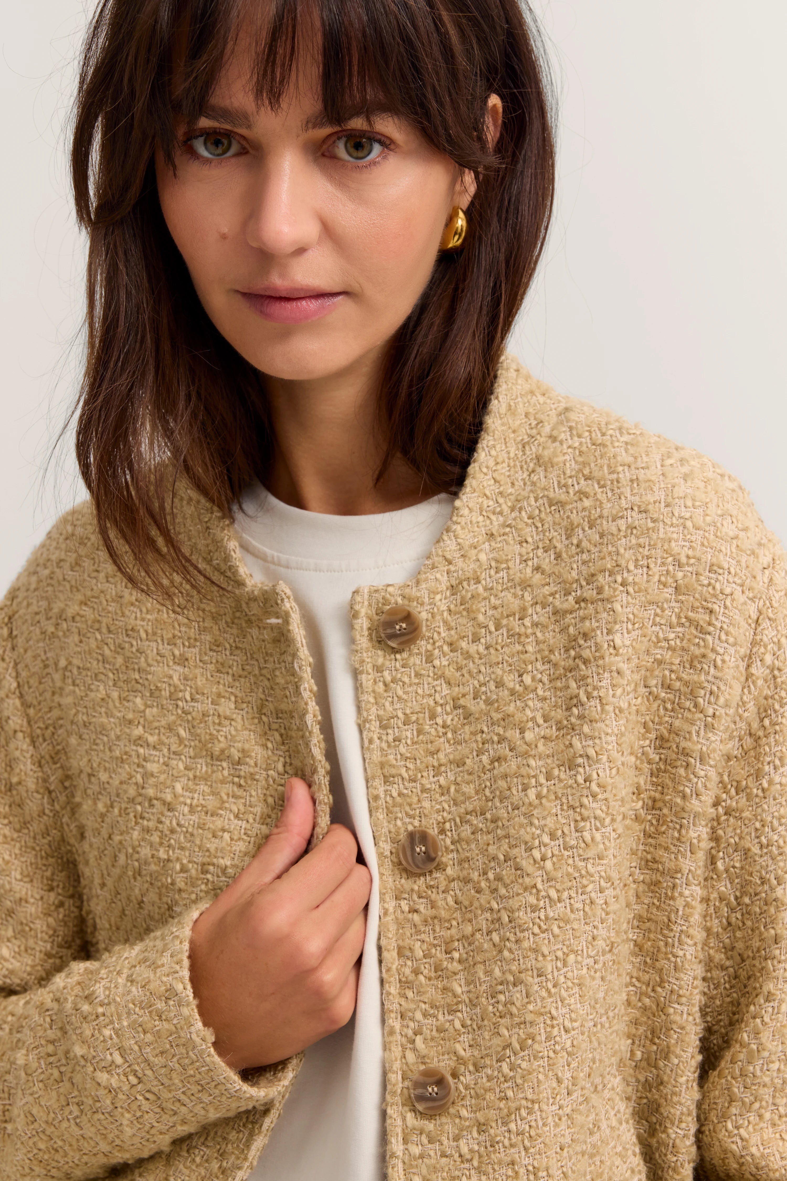 Beige Strickjacke über weißem Shirt, Büstenbild, dezente Eleganz von bugatti.