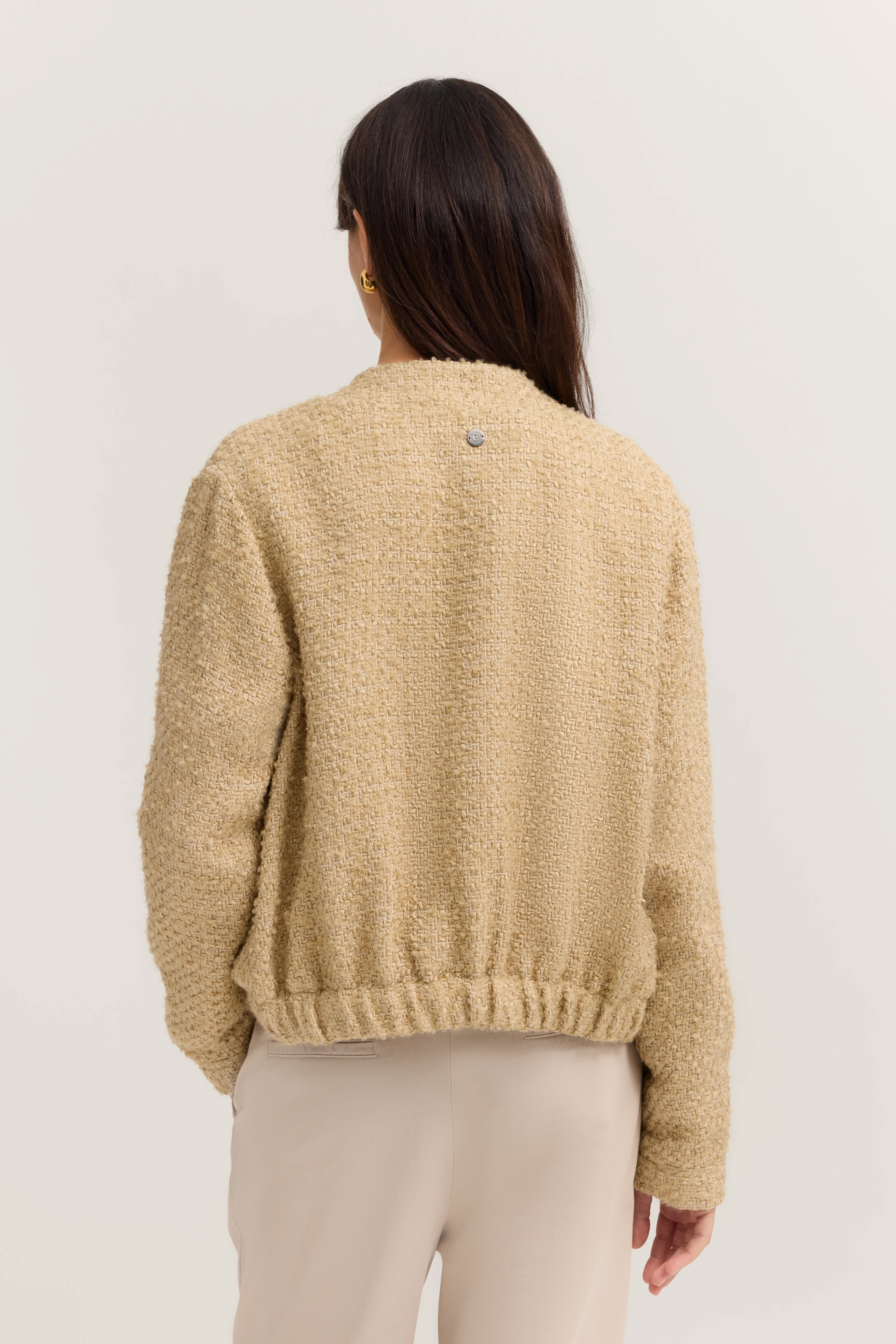 Beige Bouclé-Jacke von bugatti, Rückenansicht, kombiniert mit hellbeiger Hose.