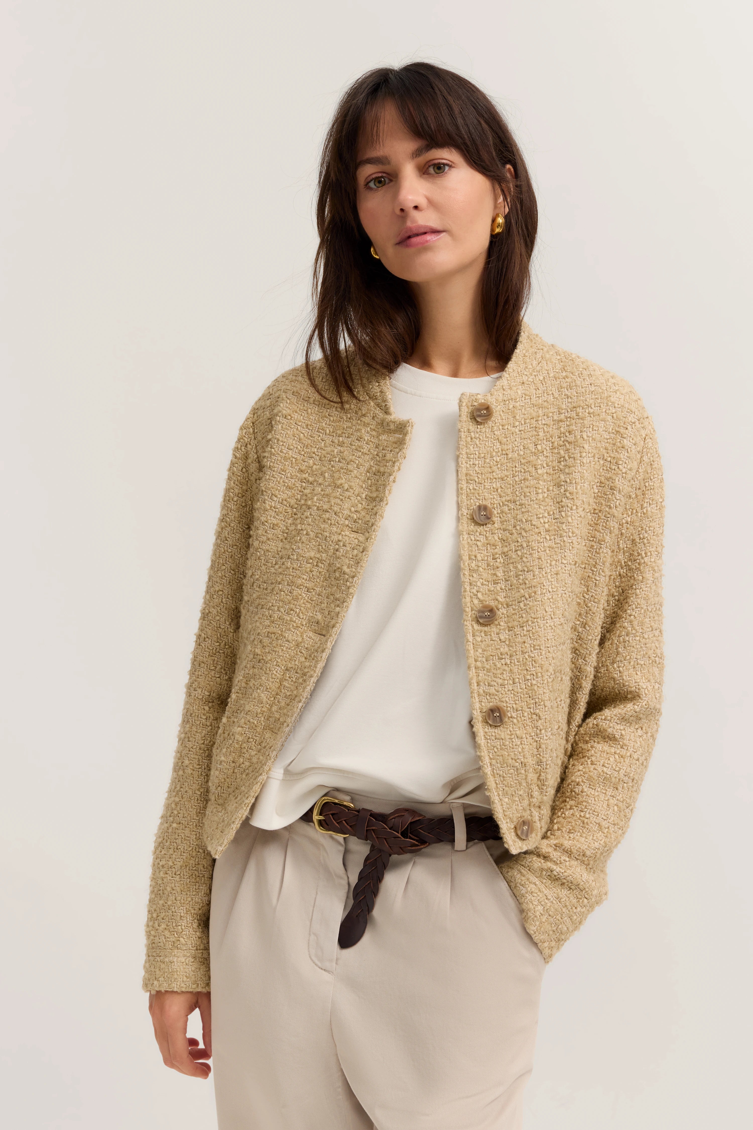 Beige Jacke und weiße Bluse, beigefarbene Hose, Büstenbild, legere Pose.
