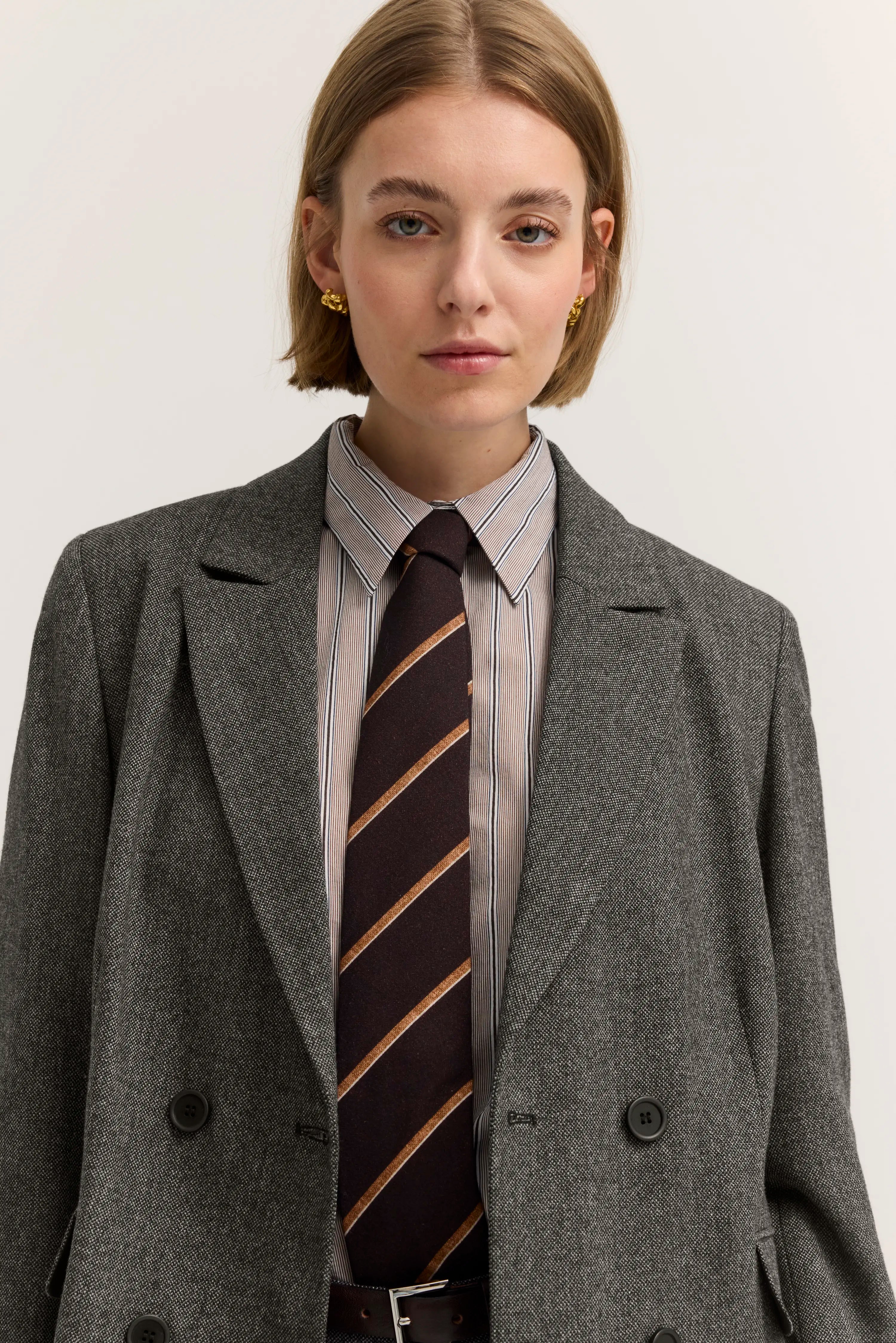 Grauer Blazer, gestreiftes Hemd, gestreifte Krawatte auf Model-Bild.