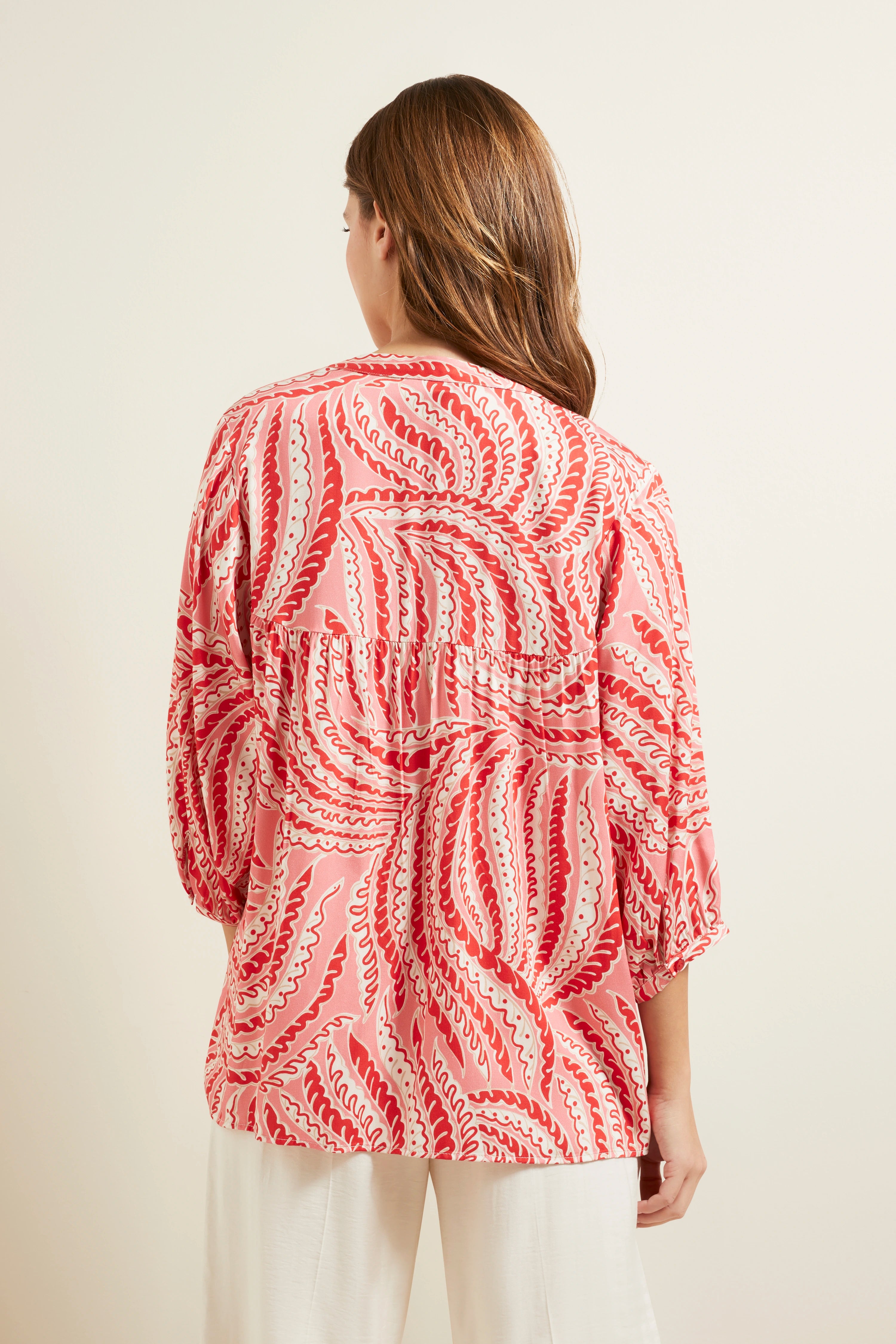 Rückansicht Model in rot-weiß gemustertem bugatti-Shirt, locker fallend, mit weißen Hosen.