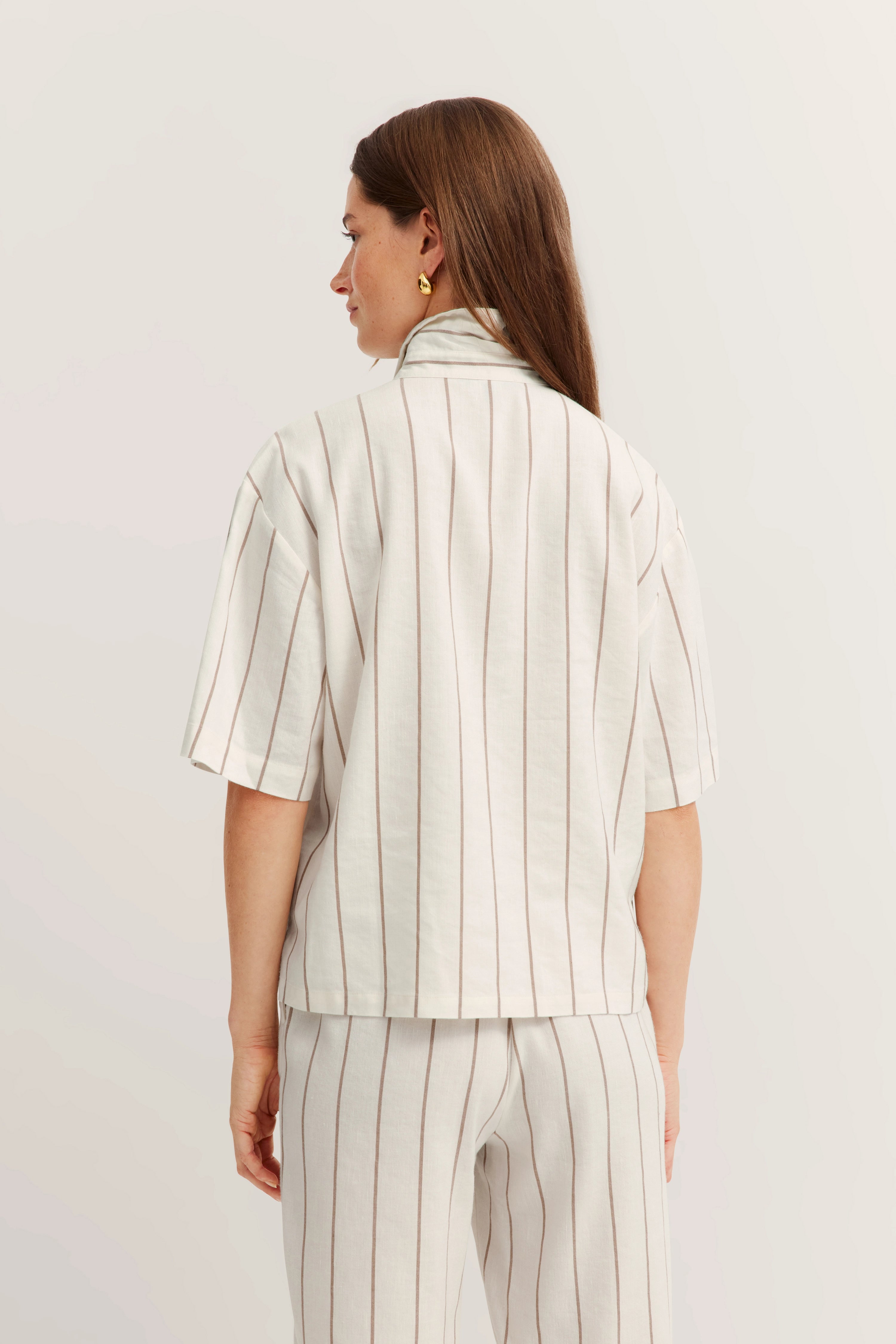 Weißes gestreiftes Set aus Oberteil und Hose, legeres Modelbild, Rückansicht, entspannte Pose.