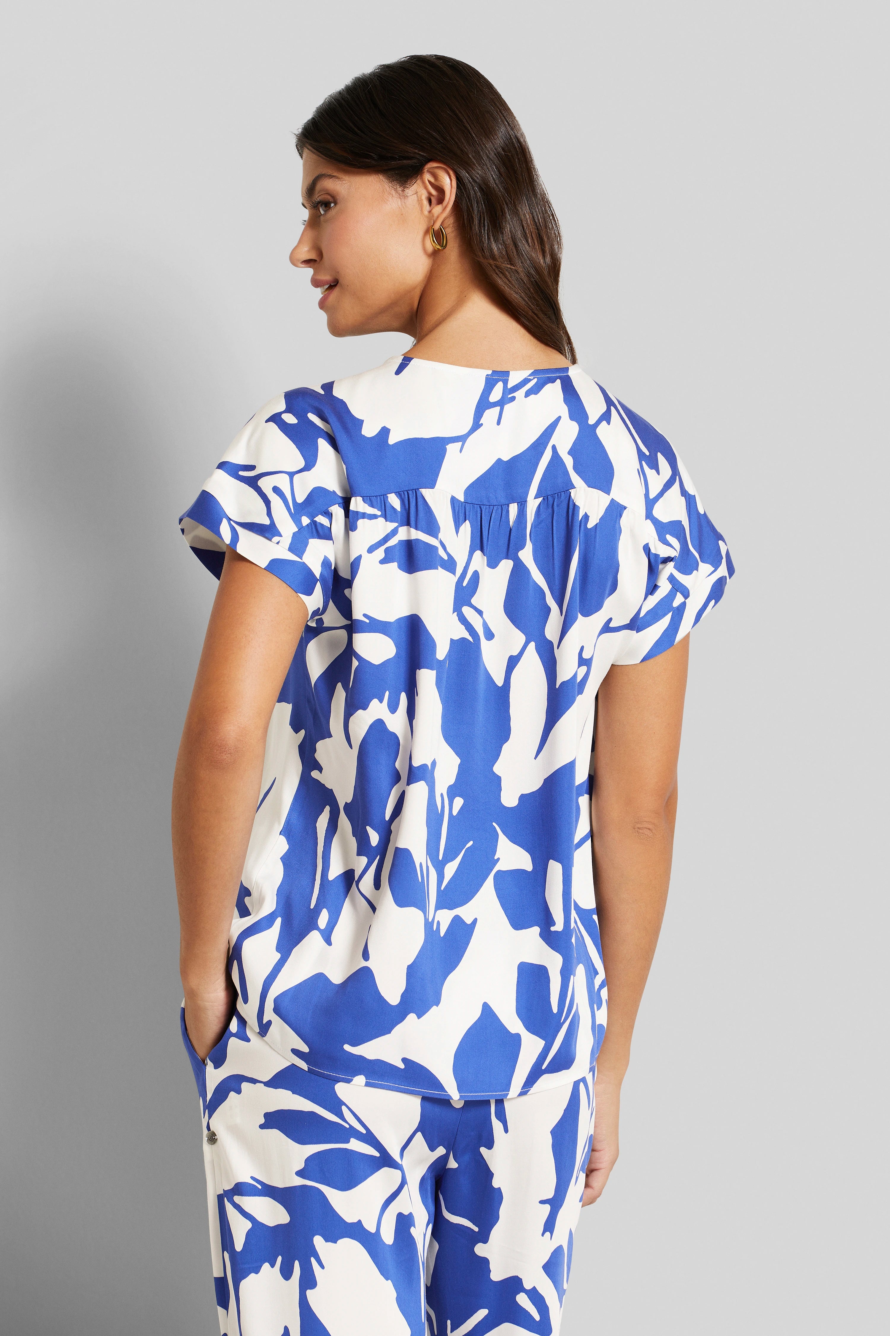 Blau-weißes Musteroutfit von bugatti, Model seitlich, lässige Pose.