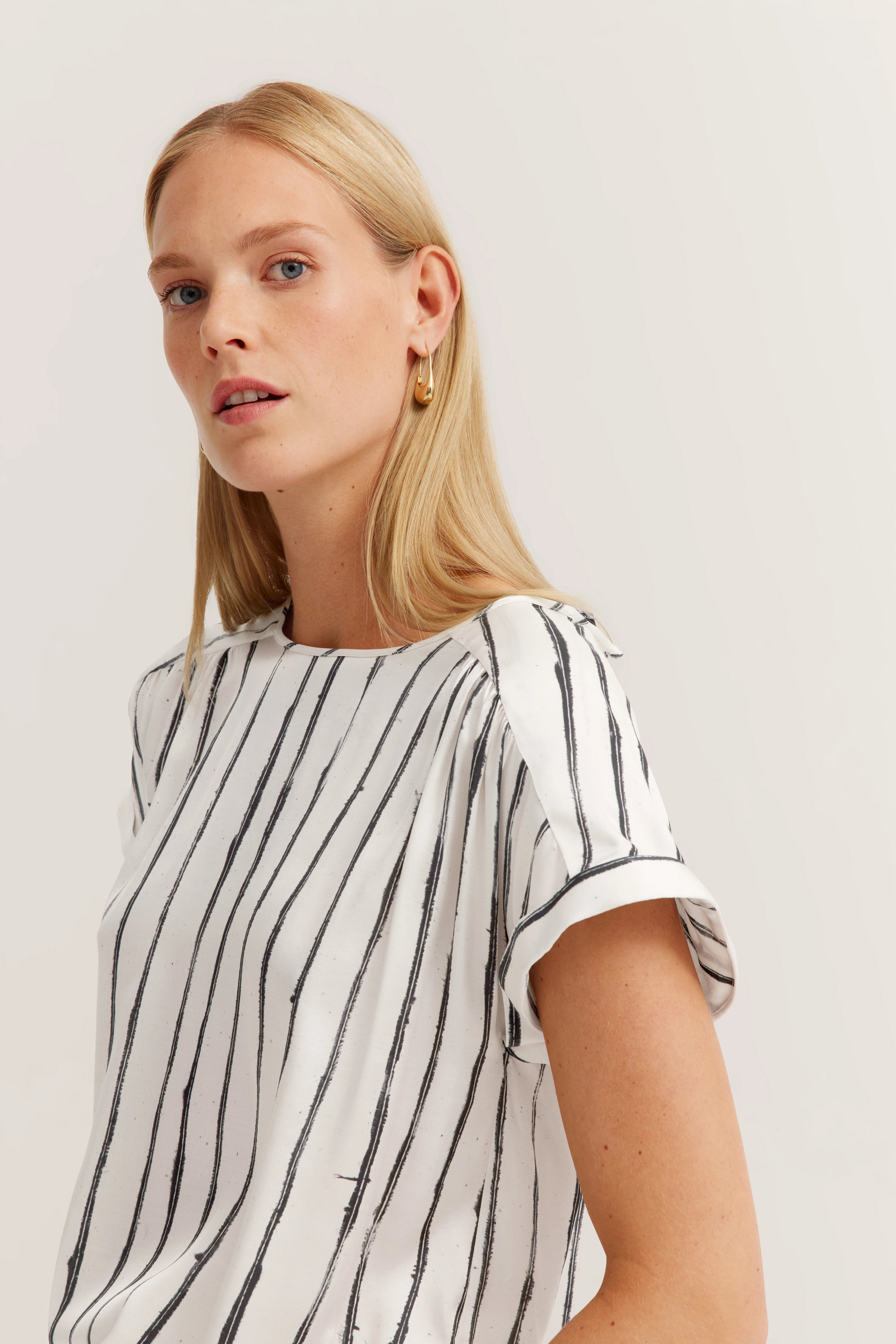 Weiße, gestreifte Bluse auf Modelbild, lässiges Posing, bugatti Stil und Eleganz.