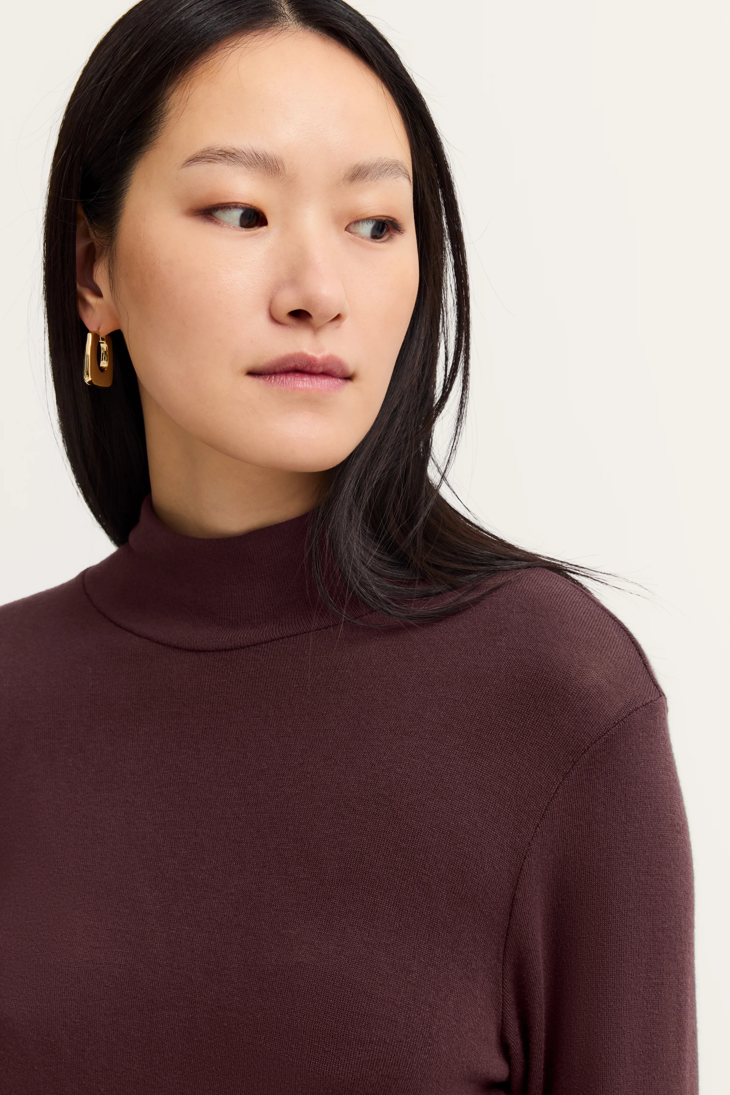 Damenmodell mit burgundfarbenem Rollkragenpullover von bugatti im legeren Büstenbild.