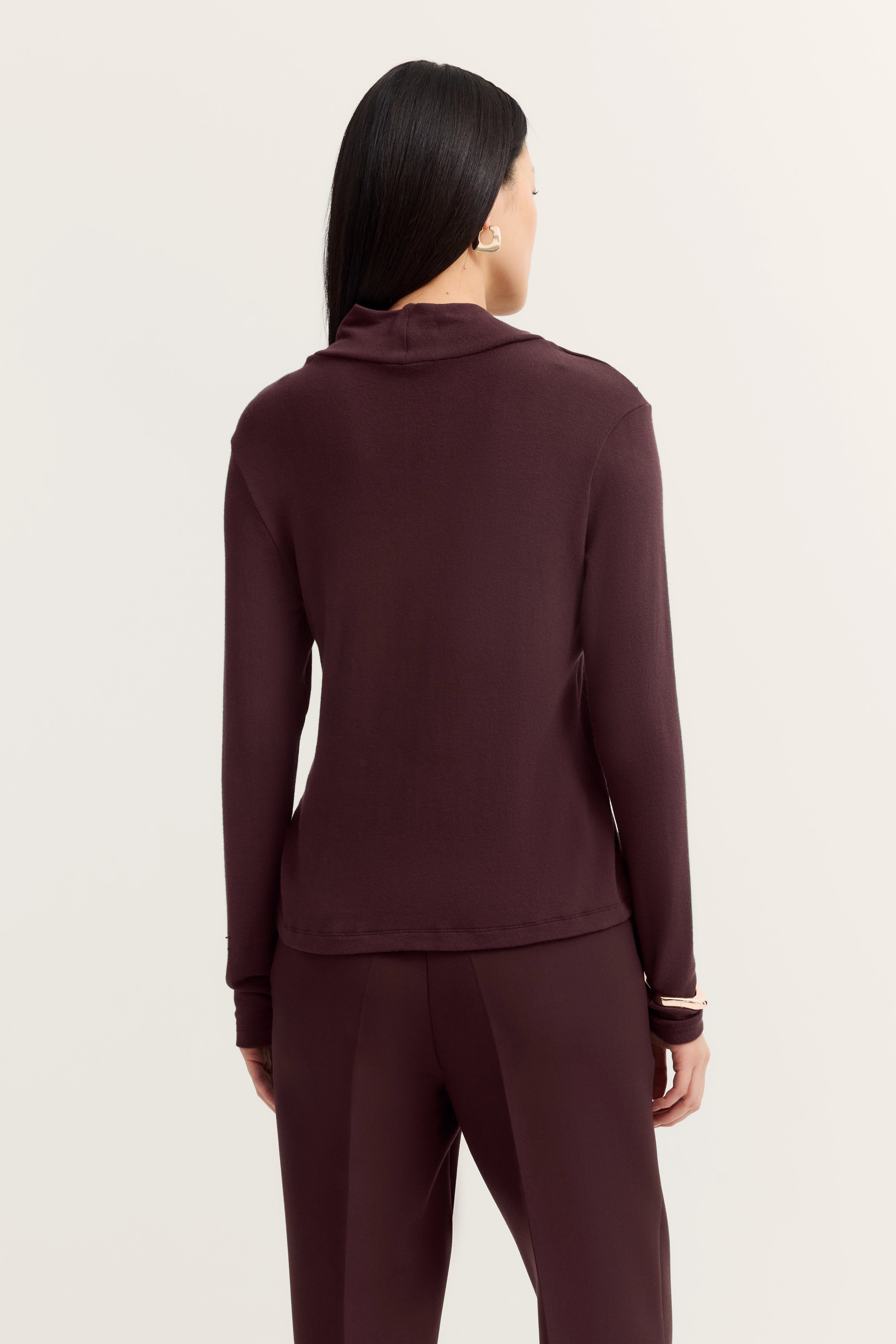 Model in bordeauxfarbenem bugatti Outfit, Pullover und Hose, Rückenansicht, entspannte Pose.