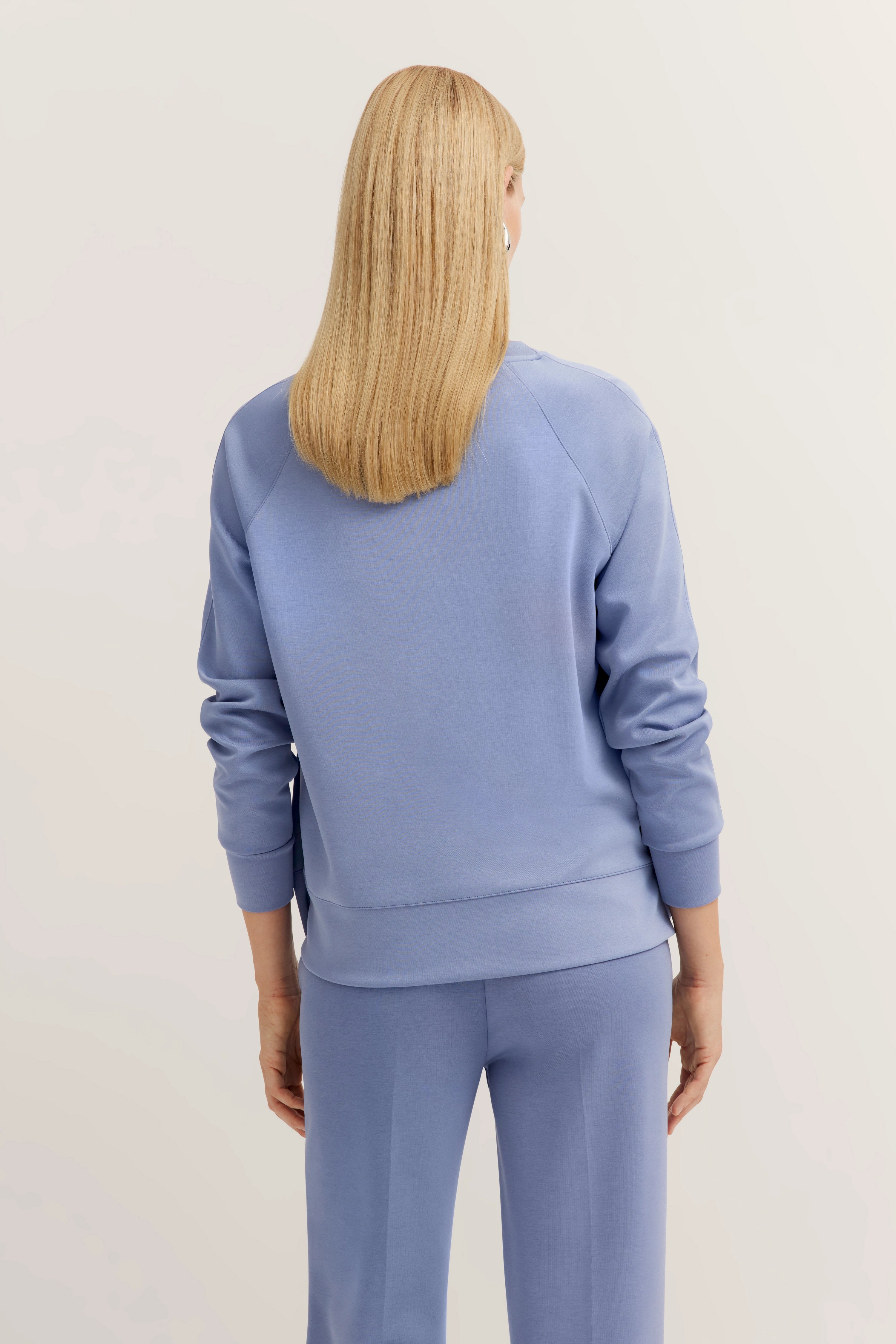 Blue bugatti lounge set with sweatshirt and pants, back view, model stands relaxed.