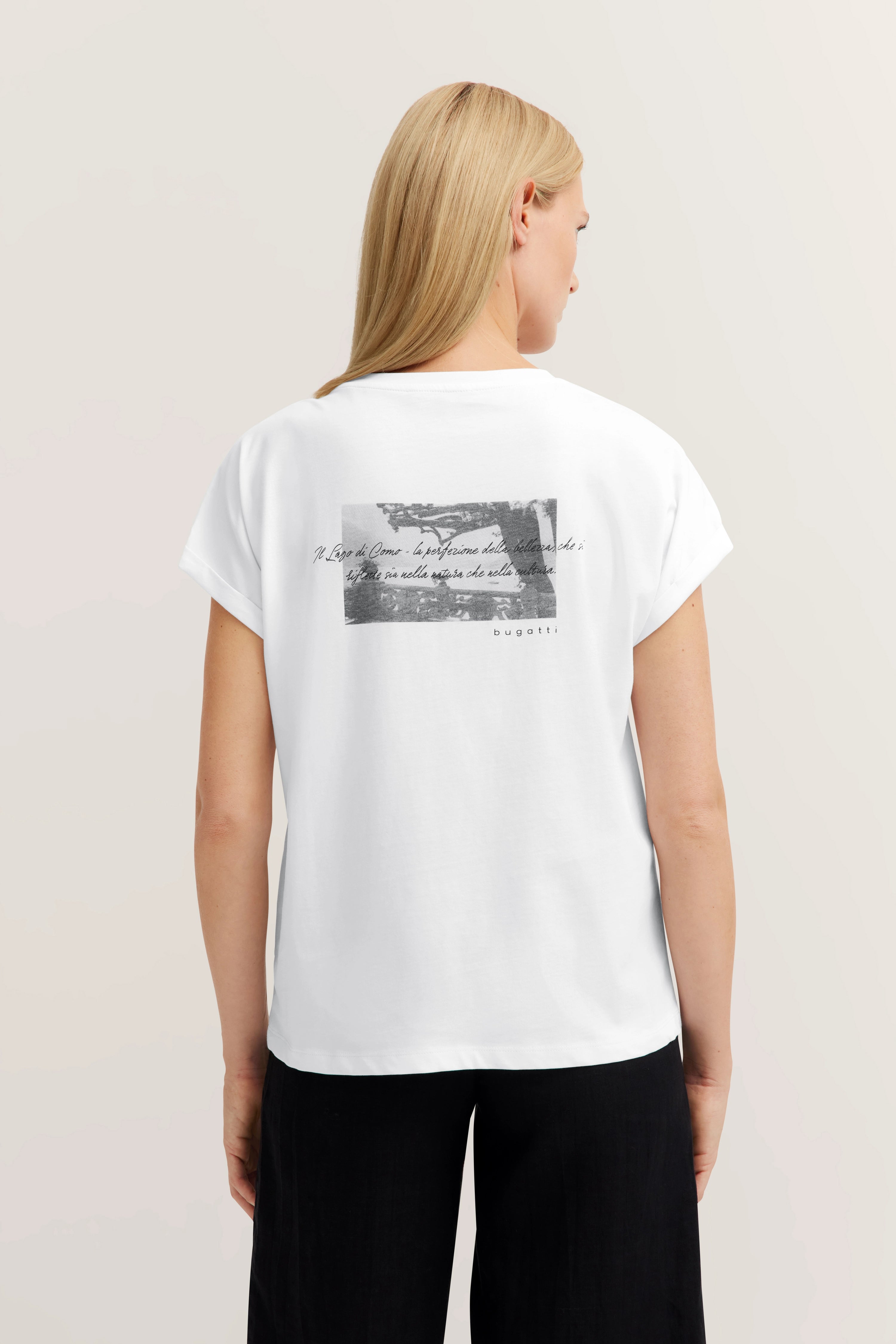 Weiße bugatti T-Shirt-Rückansicht mit schwarzem Print, getragen von Model in entspannter Pose.