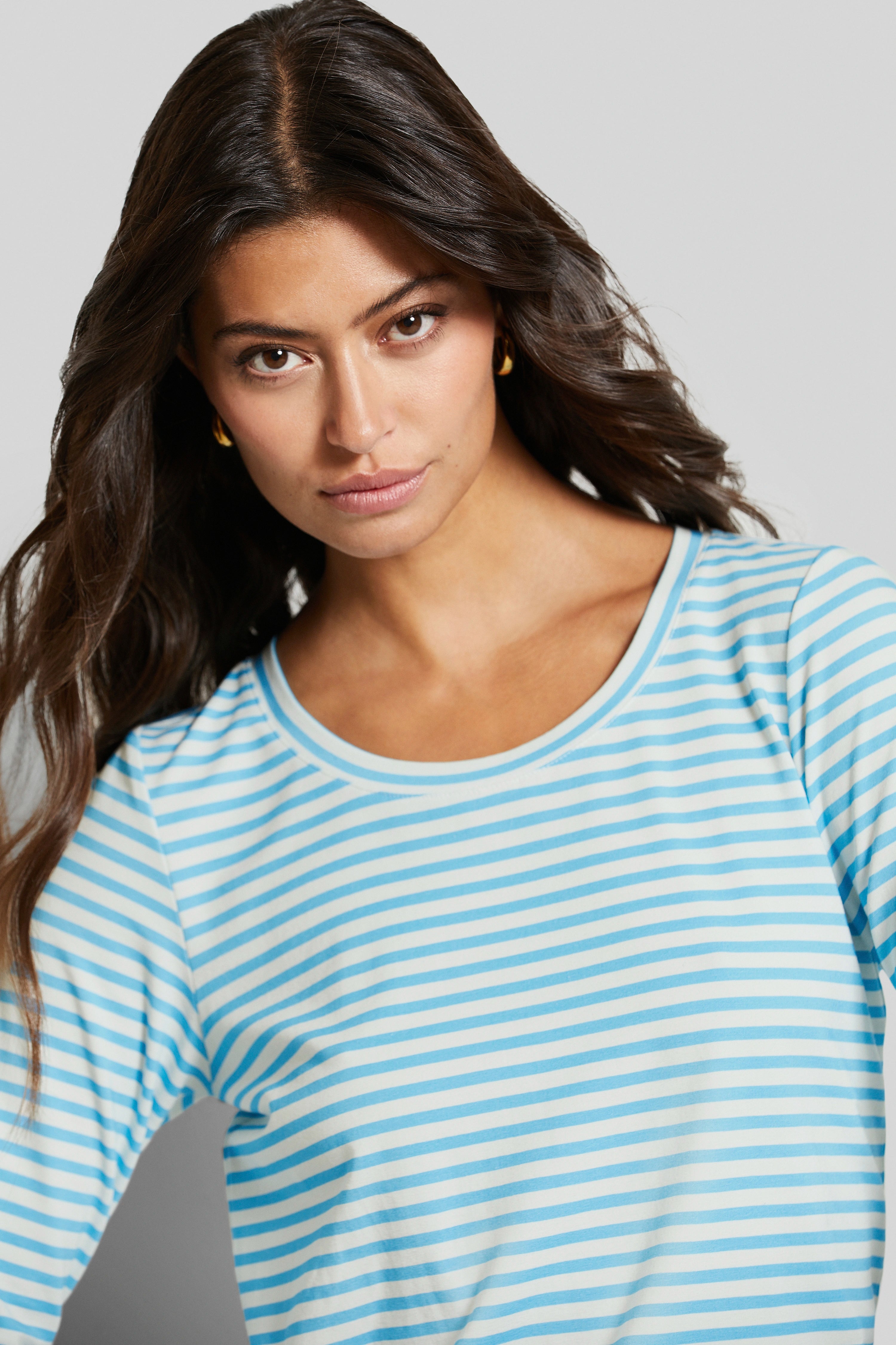 Model in blauw-wit gestreept bugatti shirt, ontspannen pose.