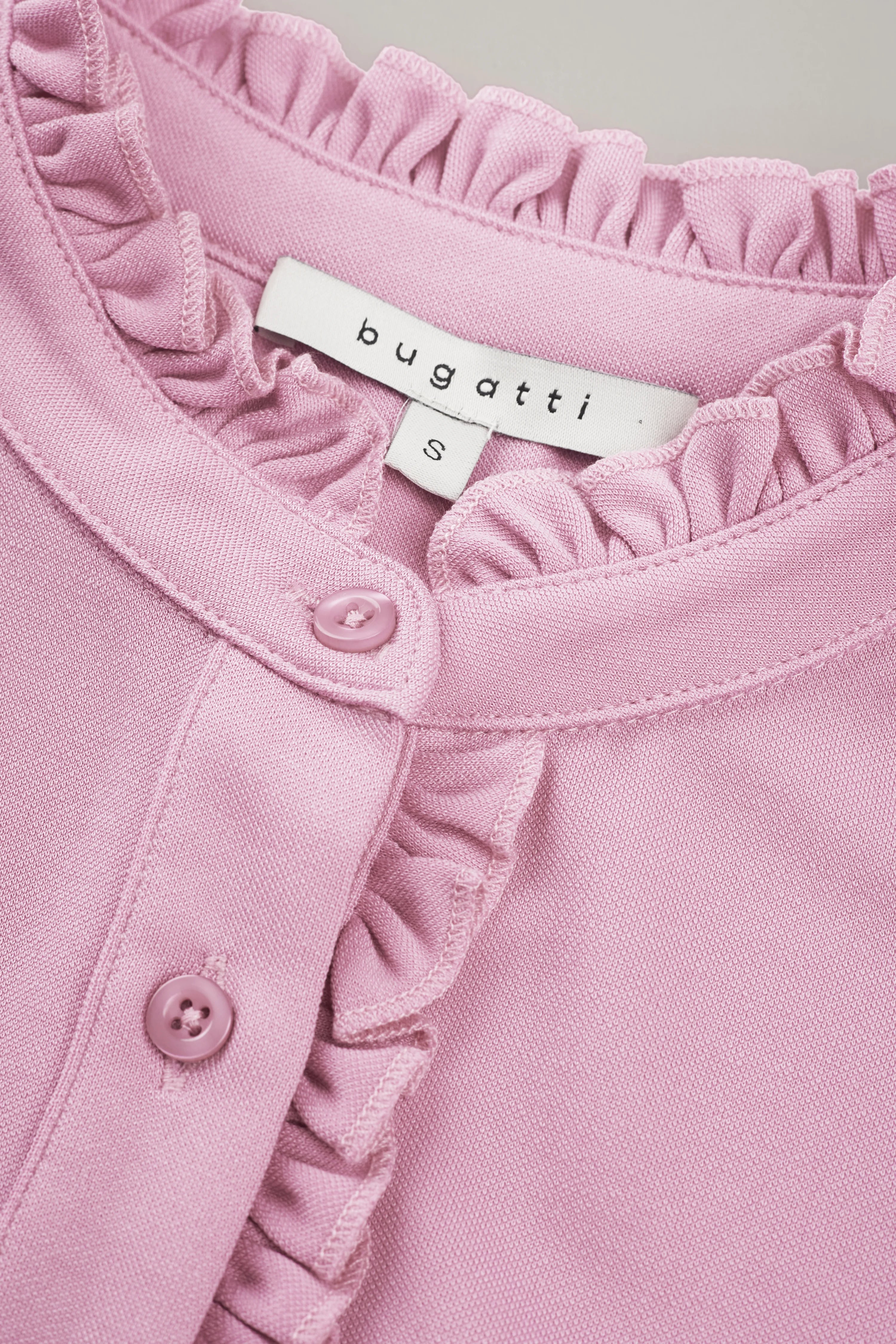 Blushfarbenes bugatti Oberteil mit Rüschen, Nahaufnahme, Büstenbild.