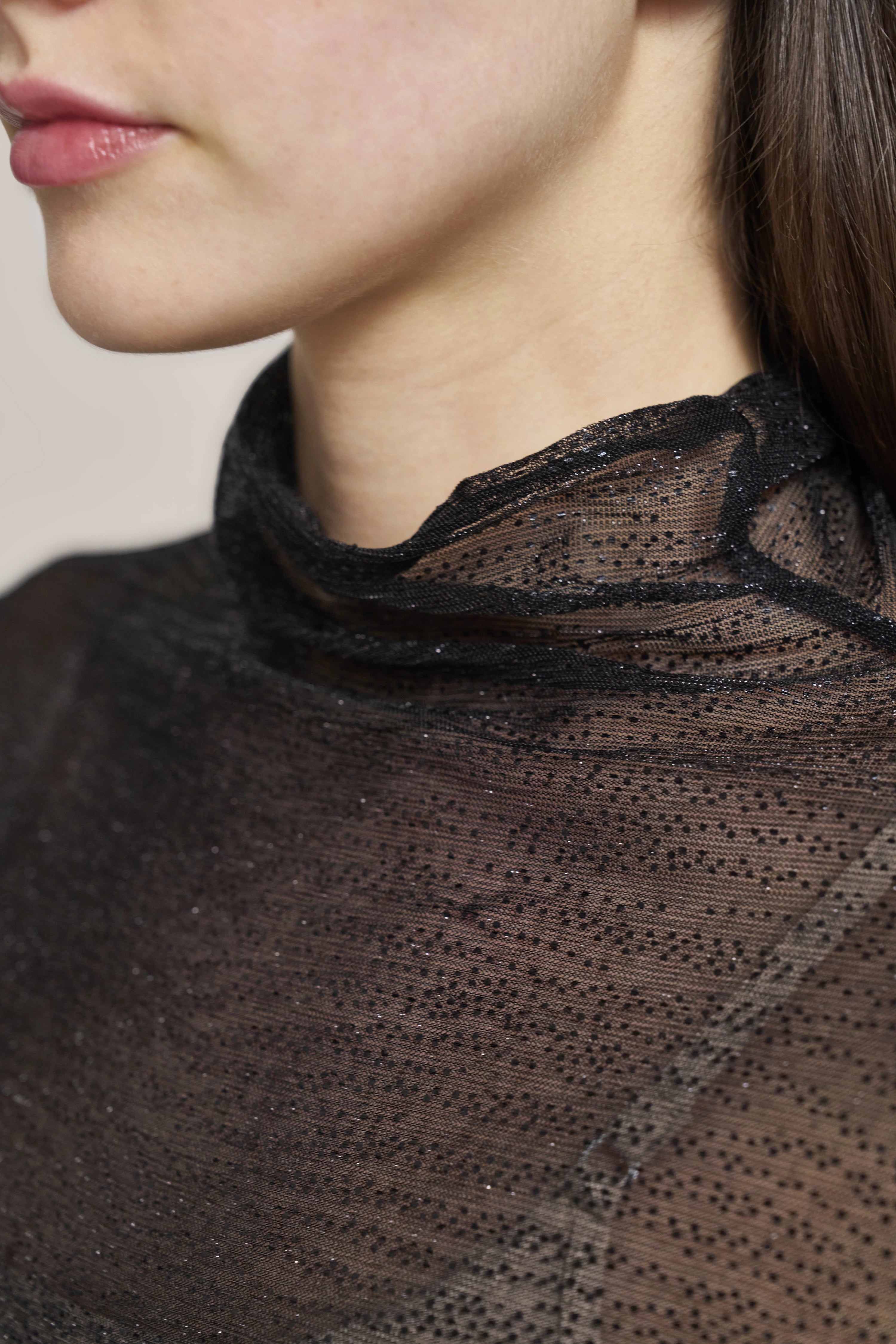 Black sheer top with glitter dots, bust view.