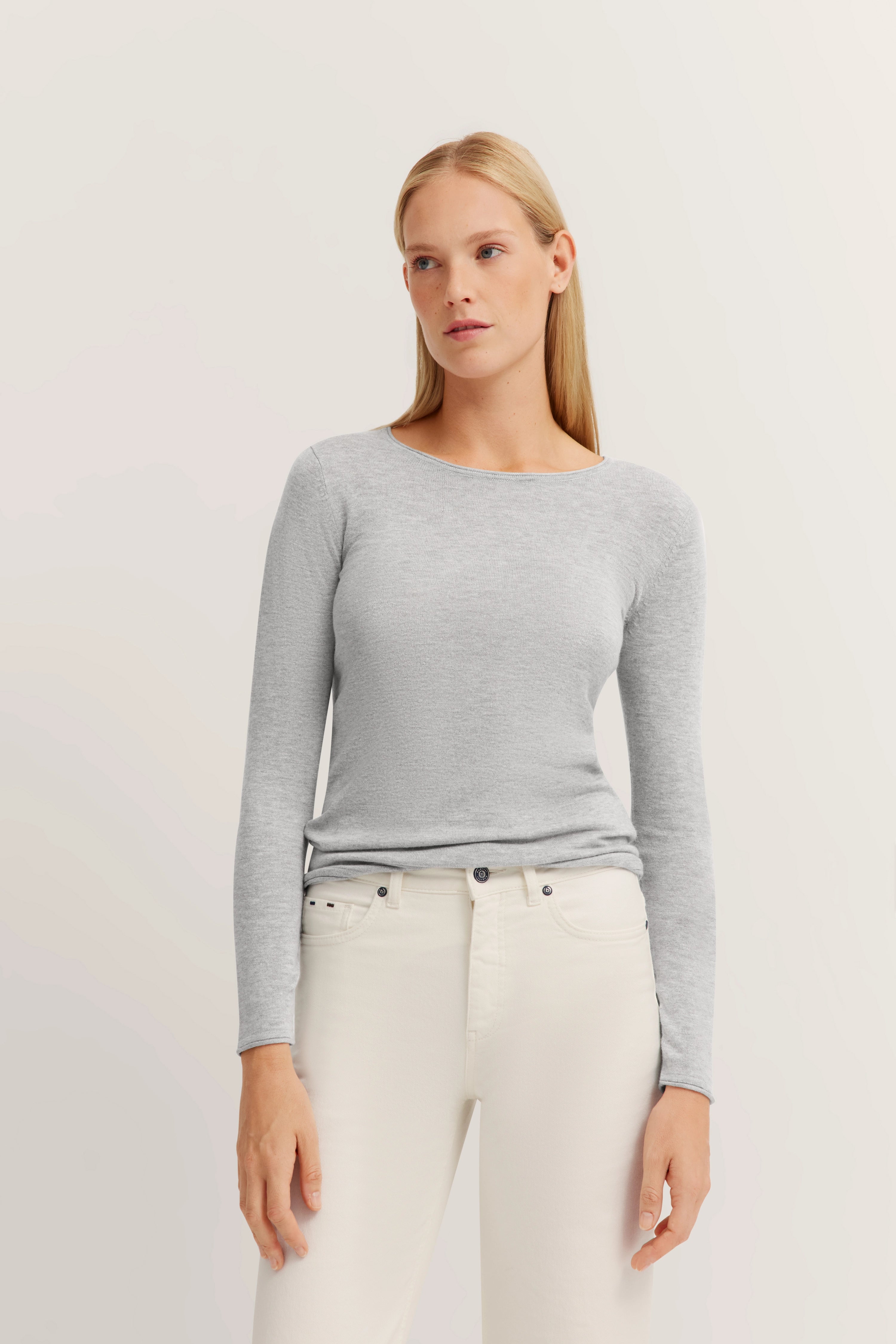Grijs bugatti langarmshirt en witte jeans, model staand, ontspannen pose.