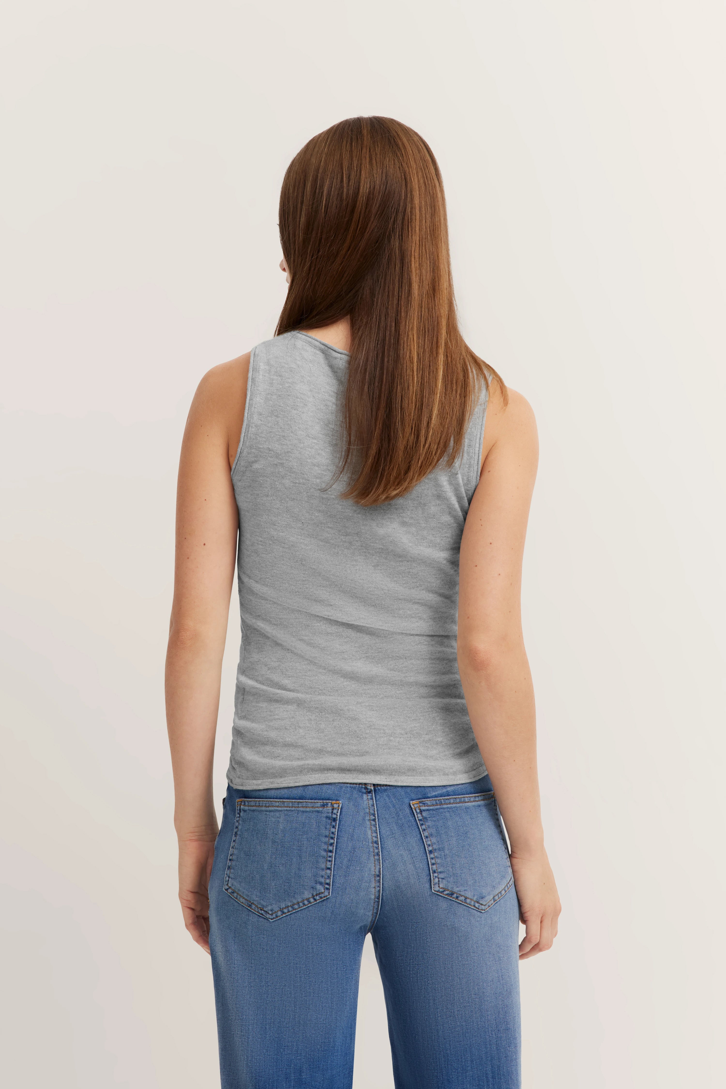 Graues ärmelloses Top und blaue Jeans, Model von hinten.