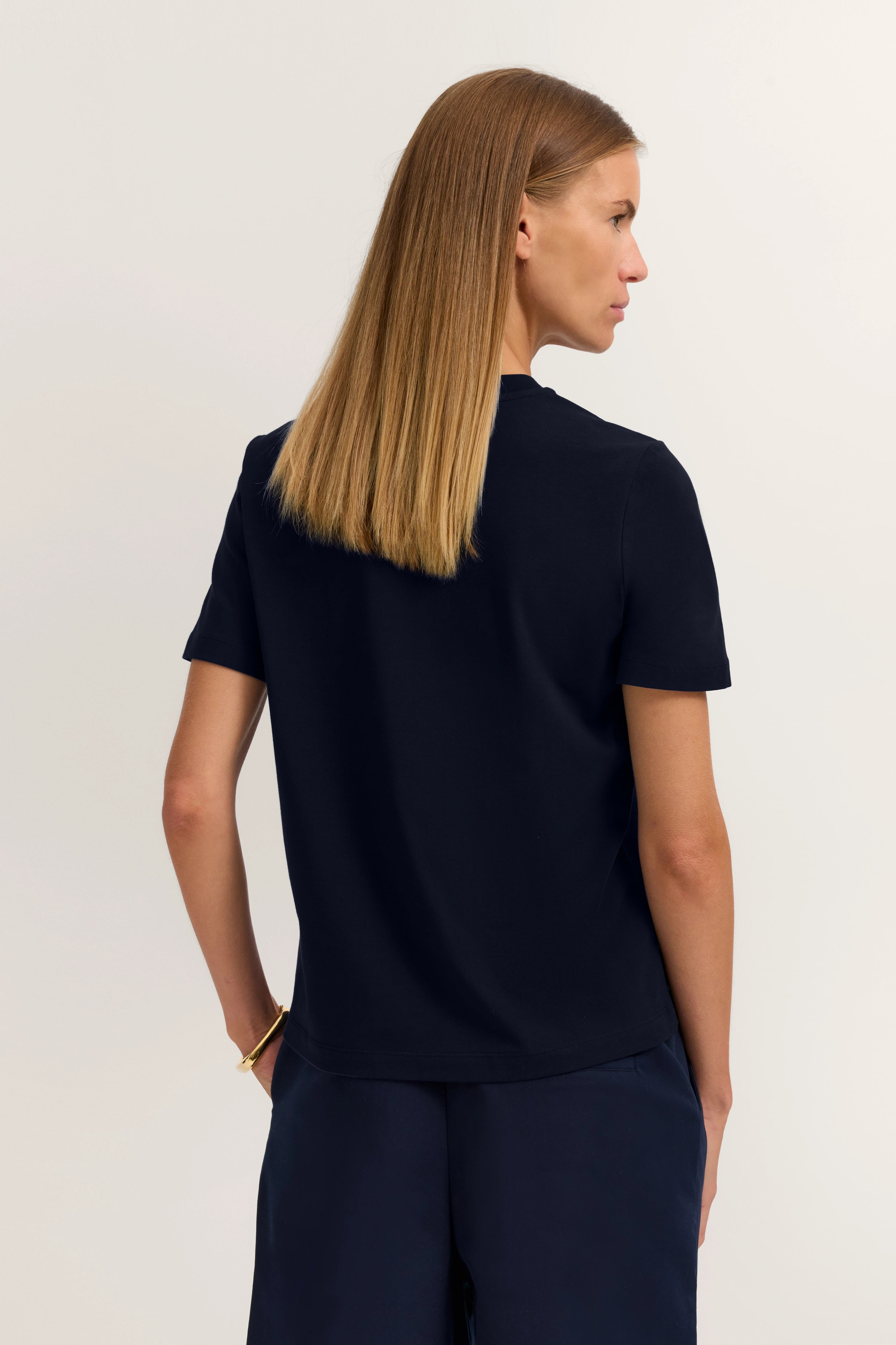 Schwarzes Shirt und Hose, Model von hinten, entspannte Pose, bugatti Stil.