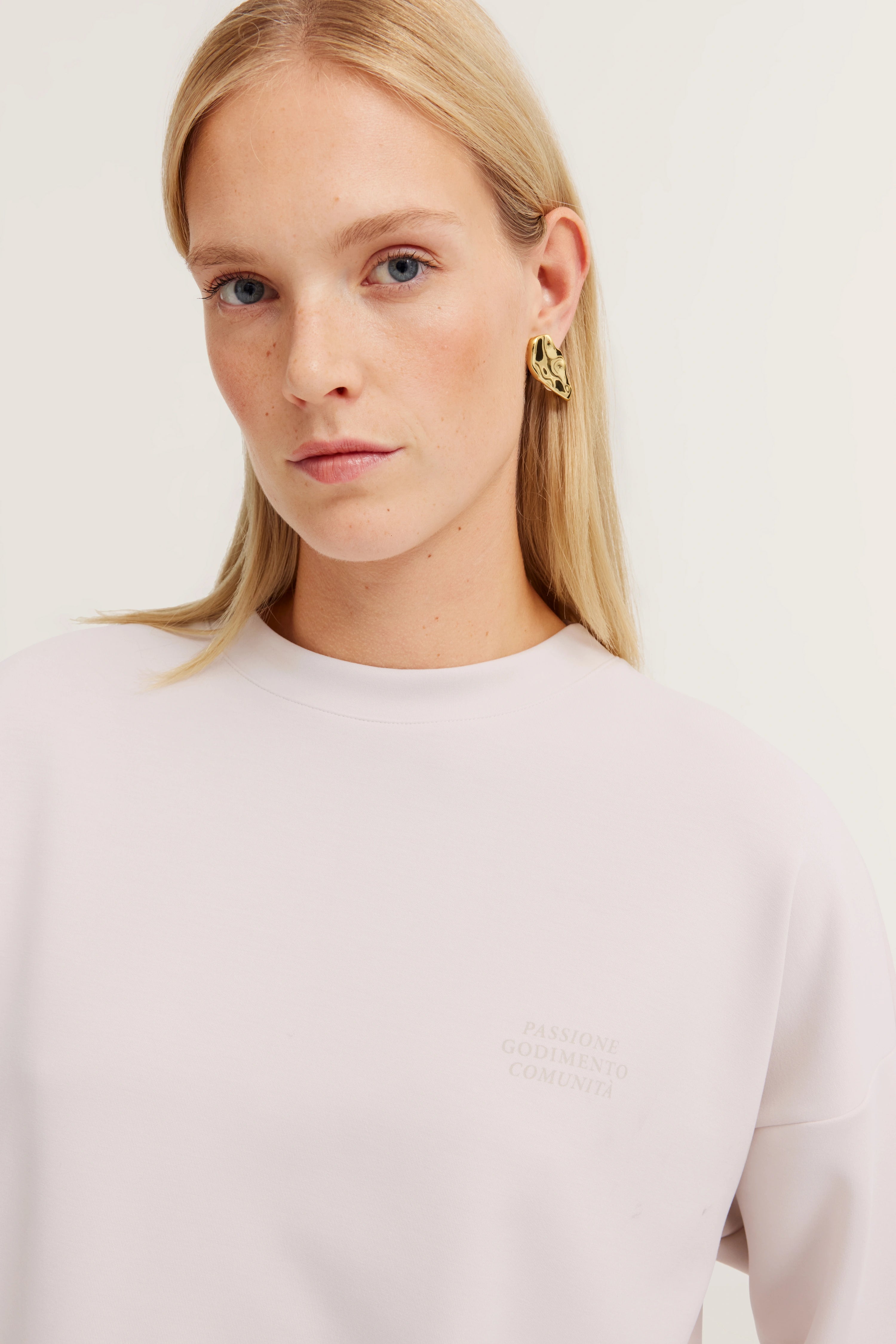 Büste mit hellem bugatti Sweatshirt, dezente Schrift, goldene Ohrringe.