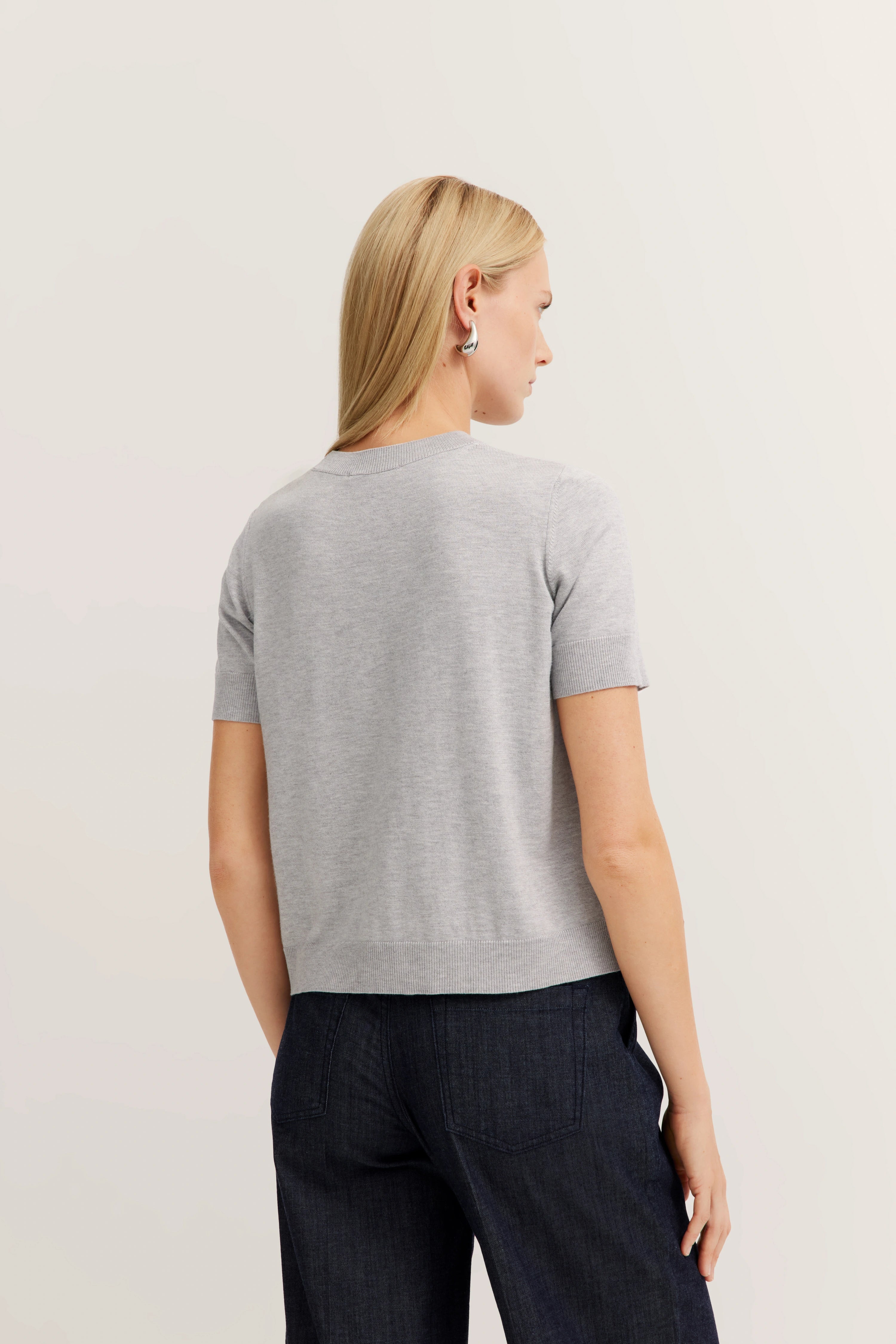 Graues Shirt, dunkelblaue Hose, Model von hinten, entspanntes Posing, bugatti Stil und Geschmack.