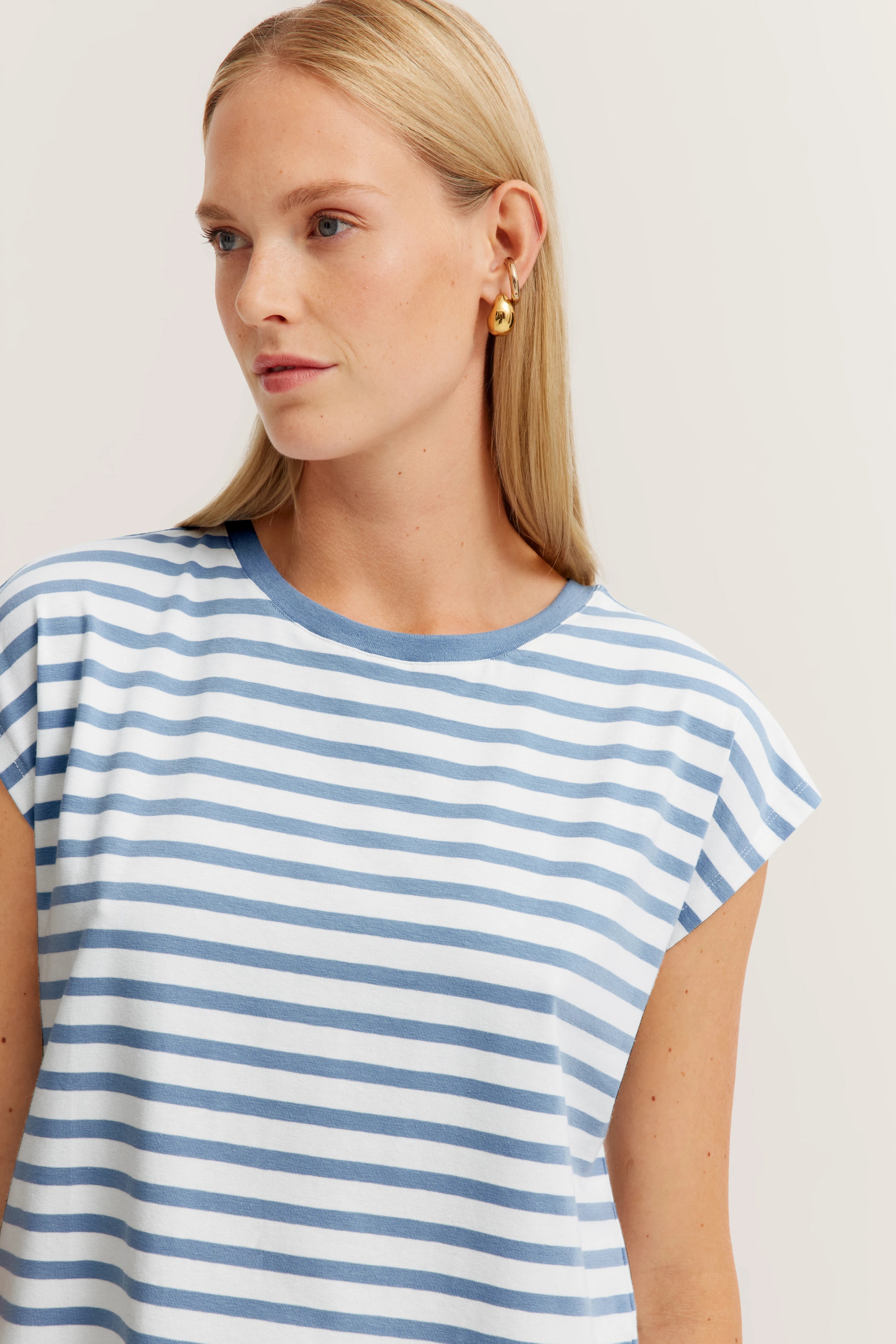 Blauw-wit gestreept T-shirt op model, ontspannen houding.