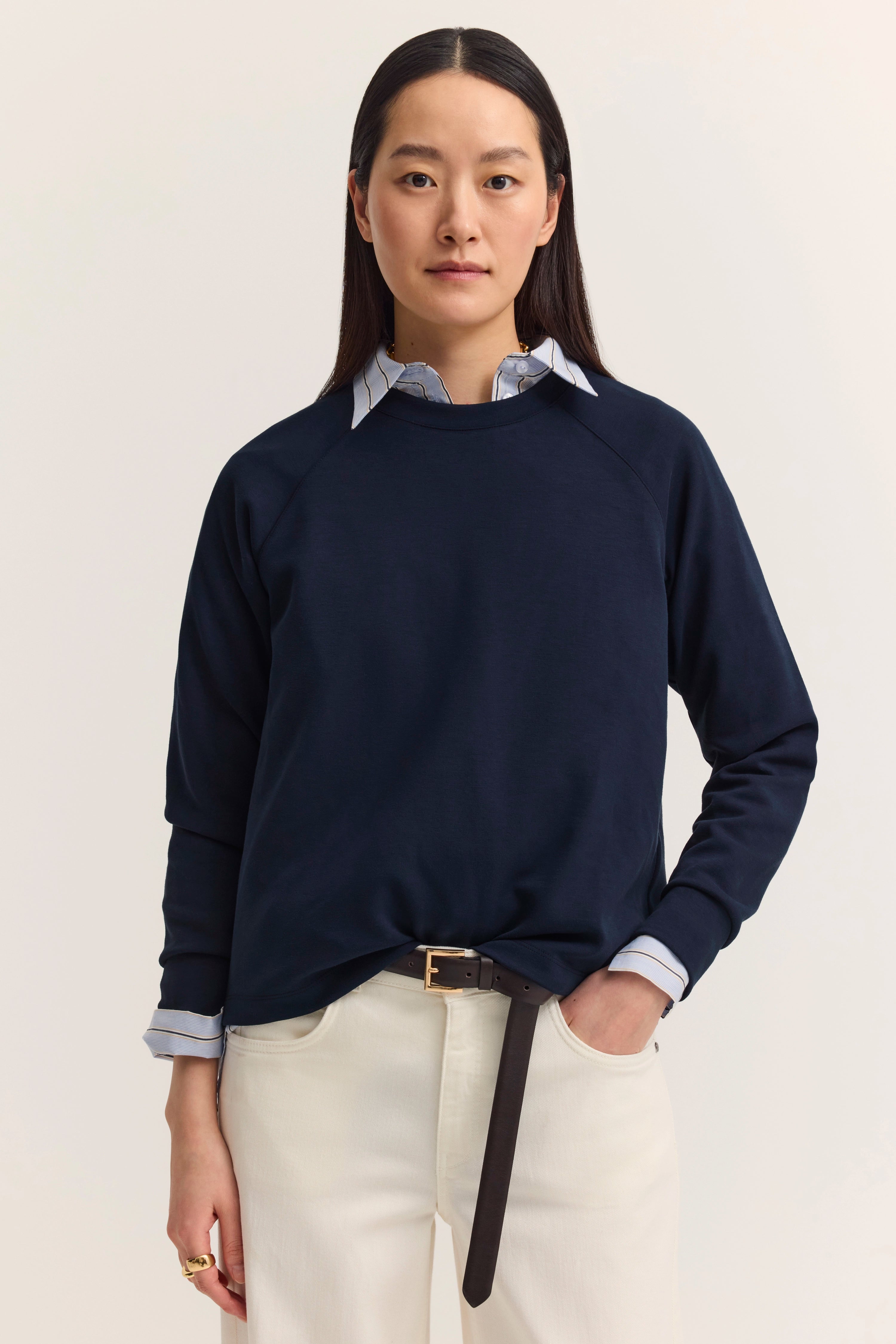 "Damenoutfit von bugatti: Dunkler Pullover über gestreiftem Hemd, helle Hose, legeres Modelbild, entspannte Pose."