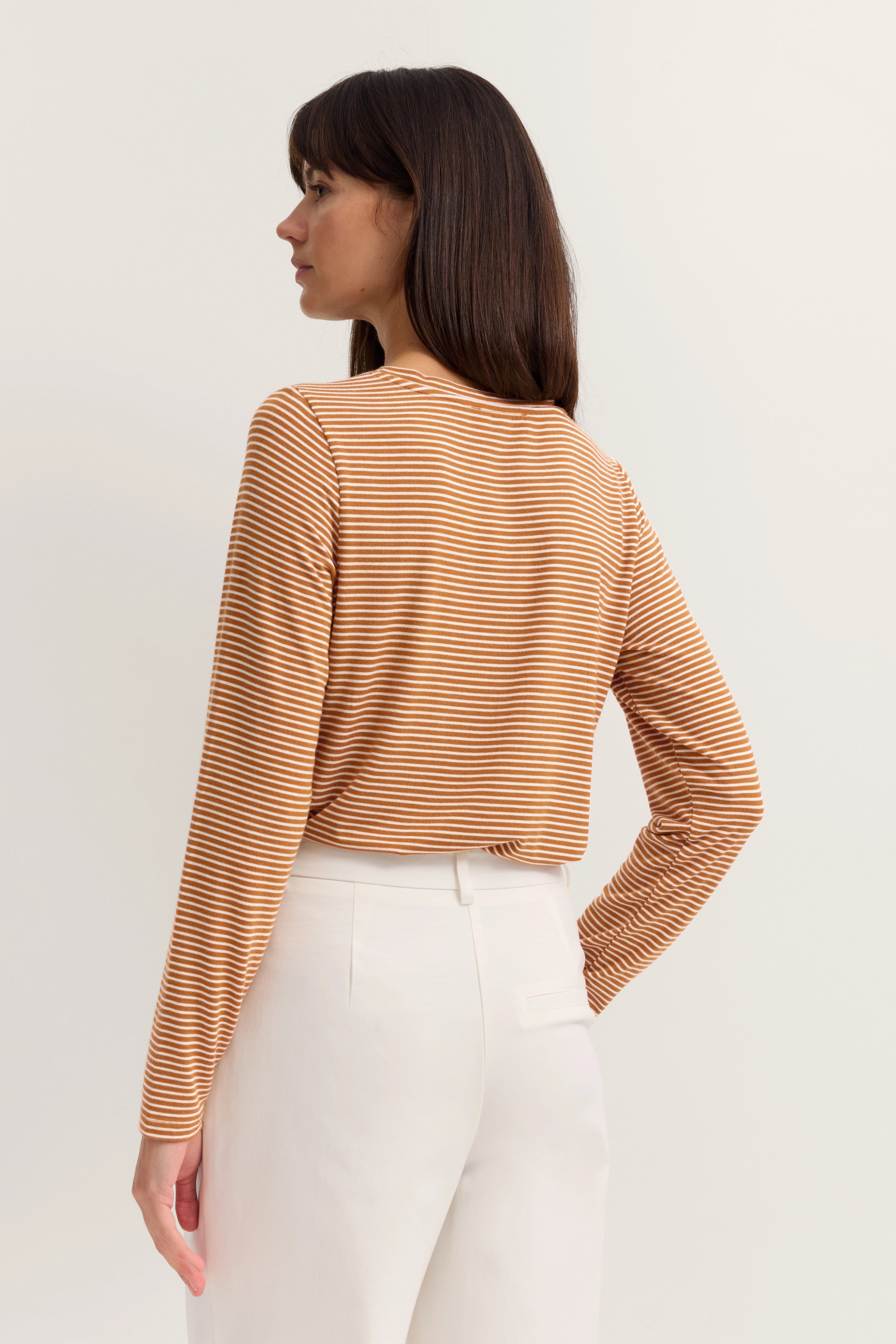 Gestreiftes Oberteil in Beige-Weiß, Model von hinten, weiße Hose, entspannte Pose, bugatti.