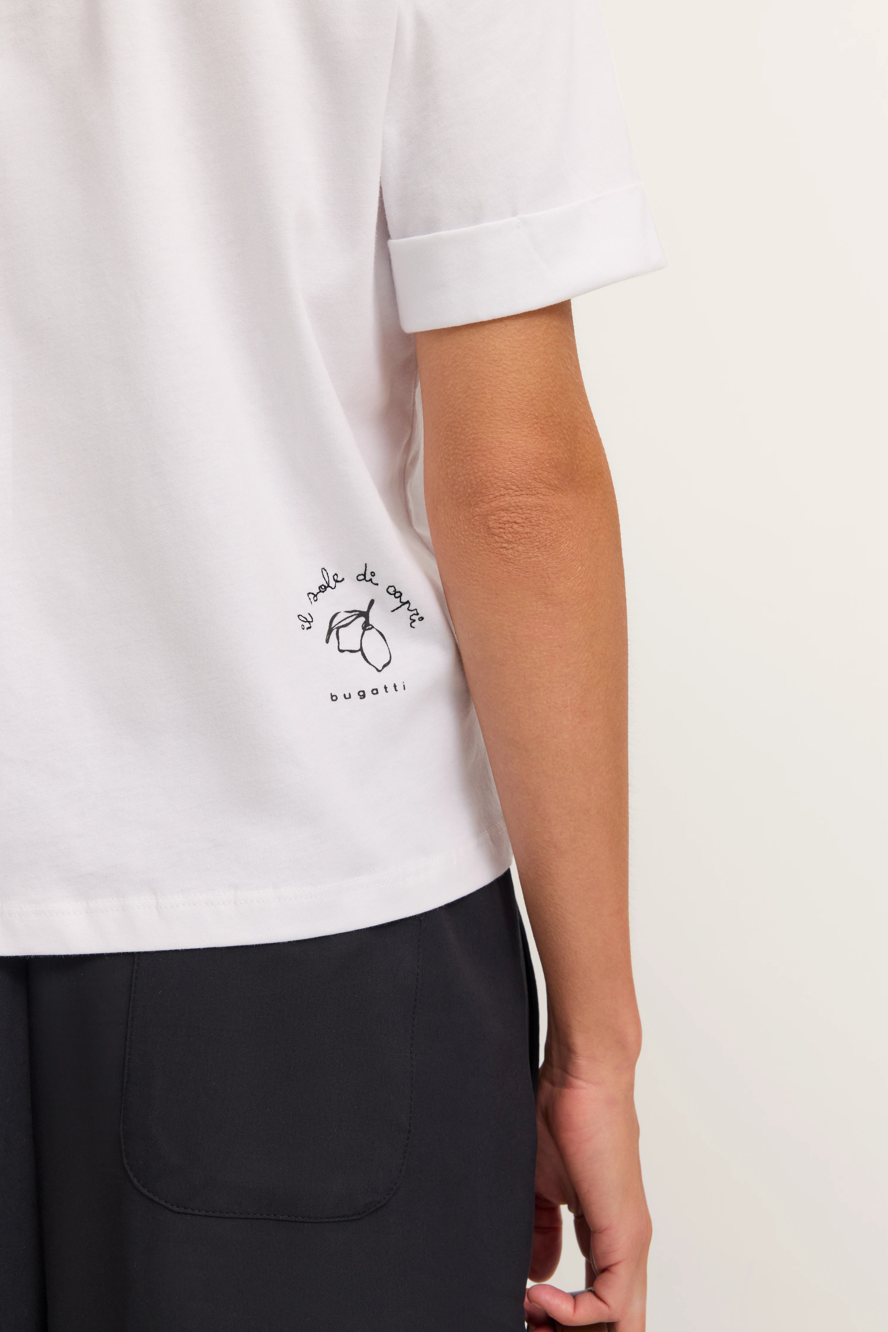Weißes bugatti T-Shirt mit Capri-Motiv, legeres Büstenbild, schwarze Hose, entspannter Stil.