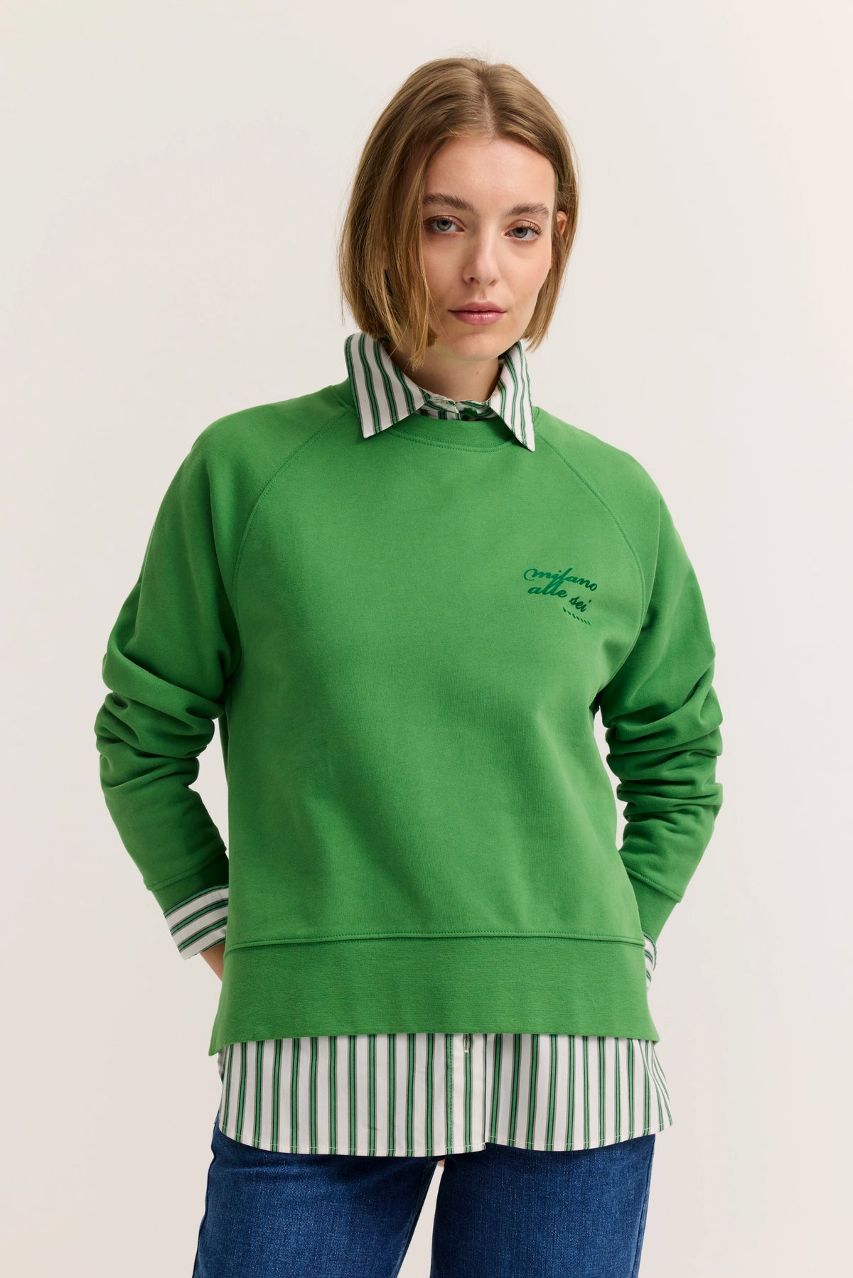 Grüner bugatti Pullover über gestreiftem Hemd, Modelbild mit lockerer Haltung.