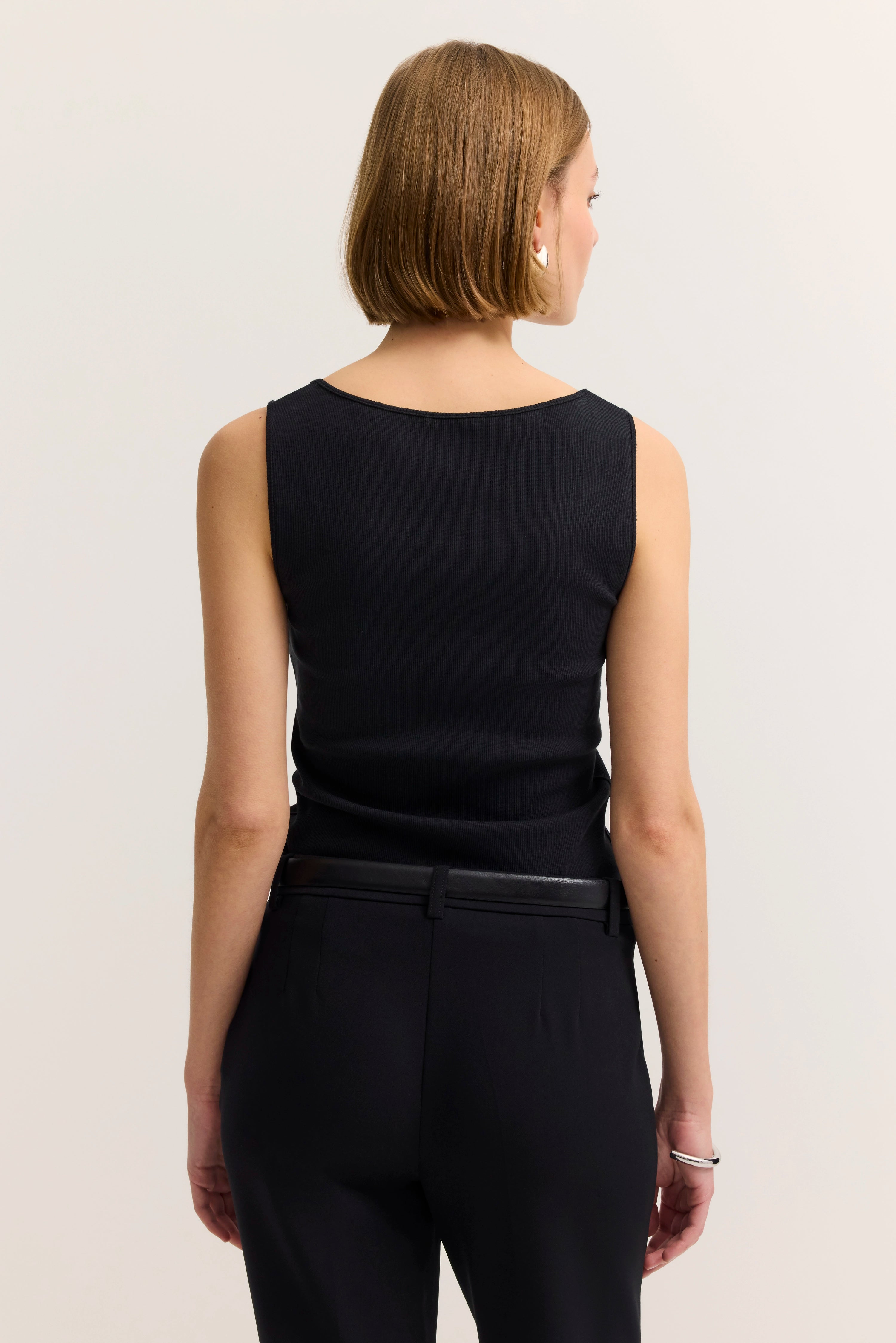 Model in schwarzem ärmellosen Top und Hose von bugatti, Rückansicht, lässiges Posing.