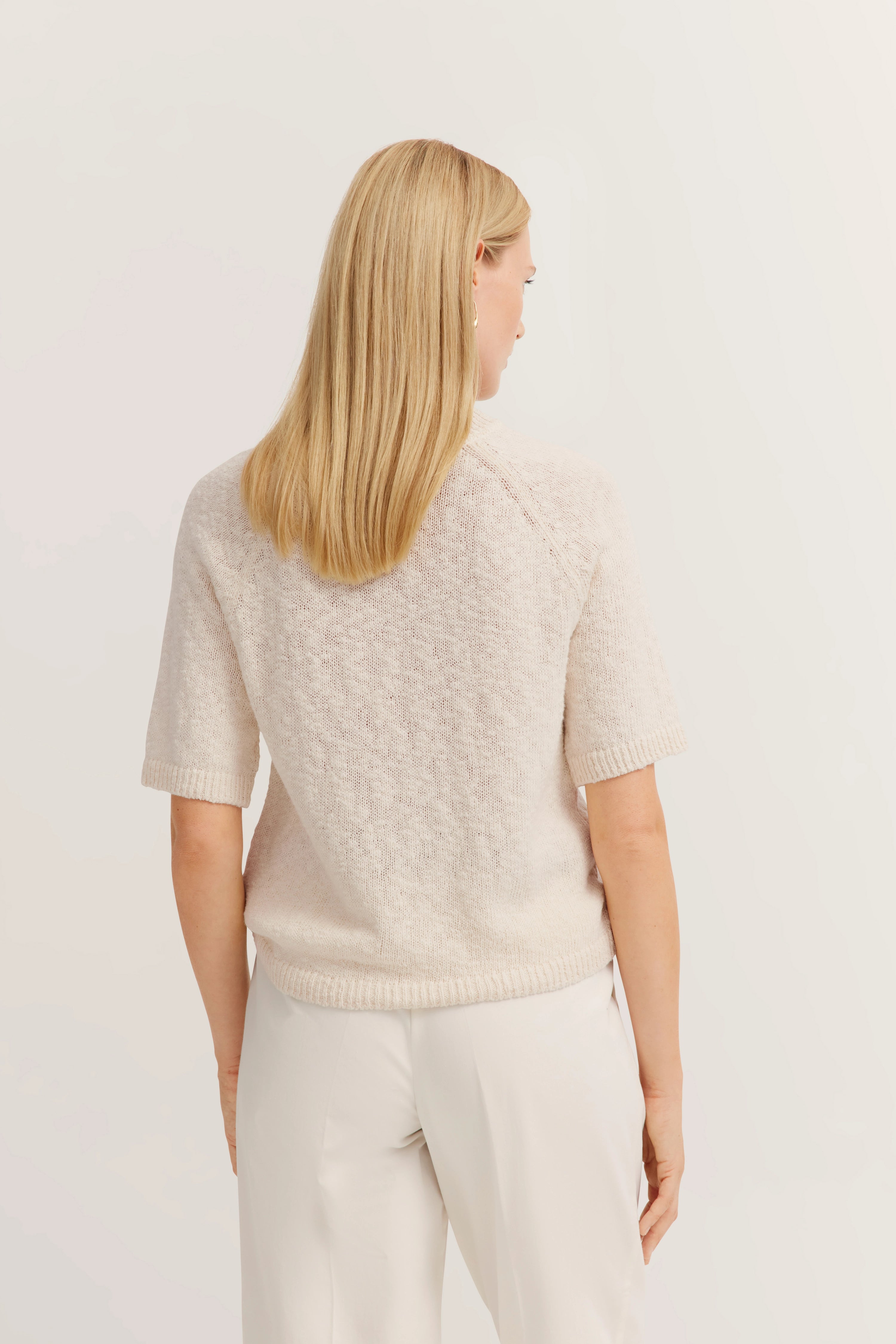 Beiger Kurzarm-Pullover und weiße Hose, Rückansicht, Modelbild, neutrales Posing.