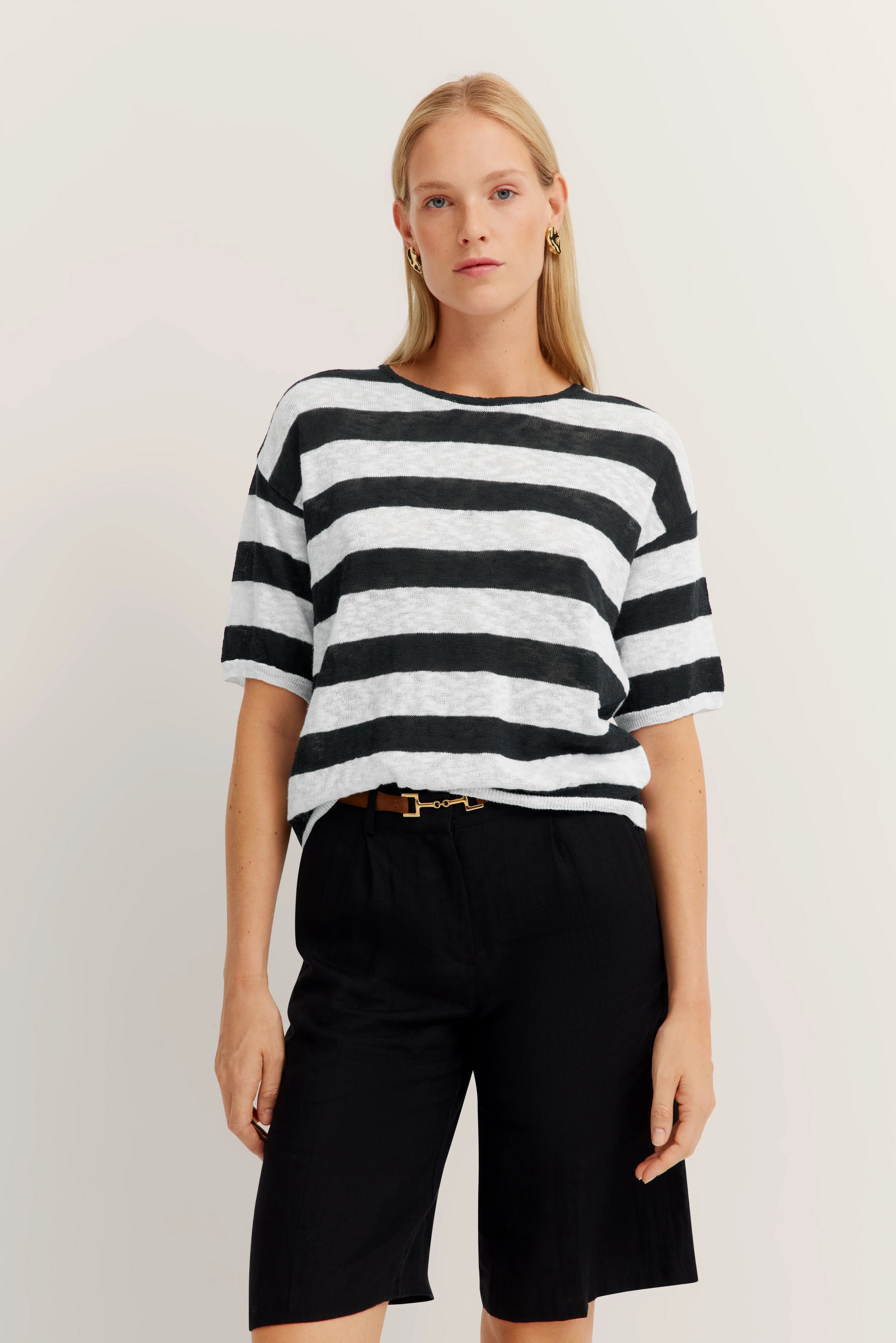 Black and white striped shirt, black shorts, casual model image.