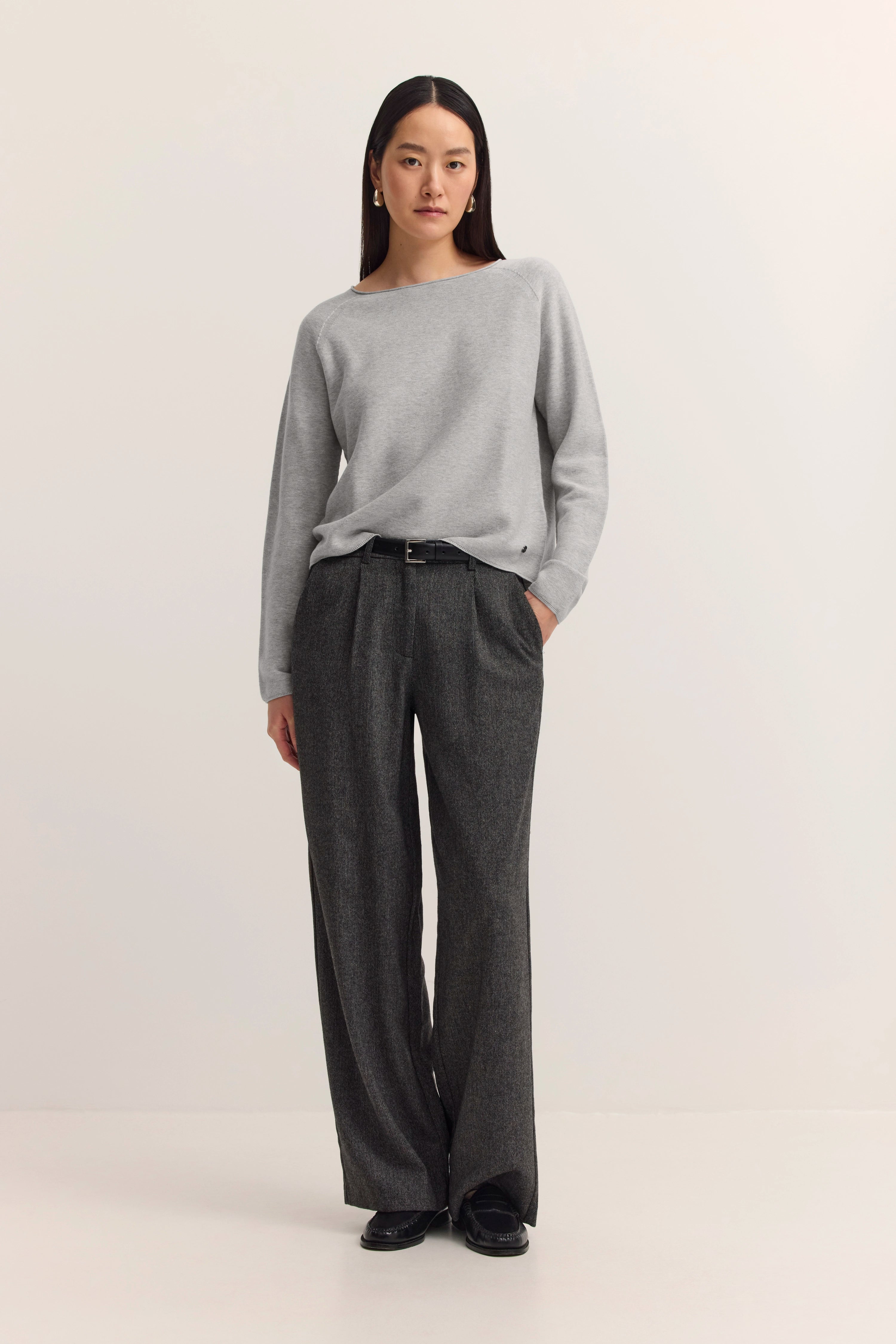 Grauer Pullover und graue Hose, Model steht entspannt. Stilvoller Look von bugatti.