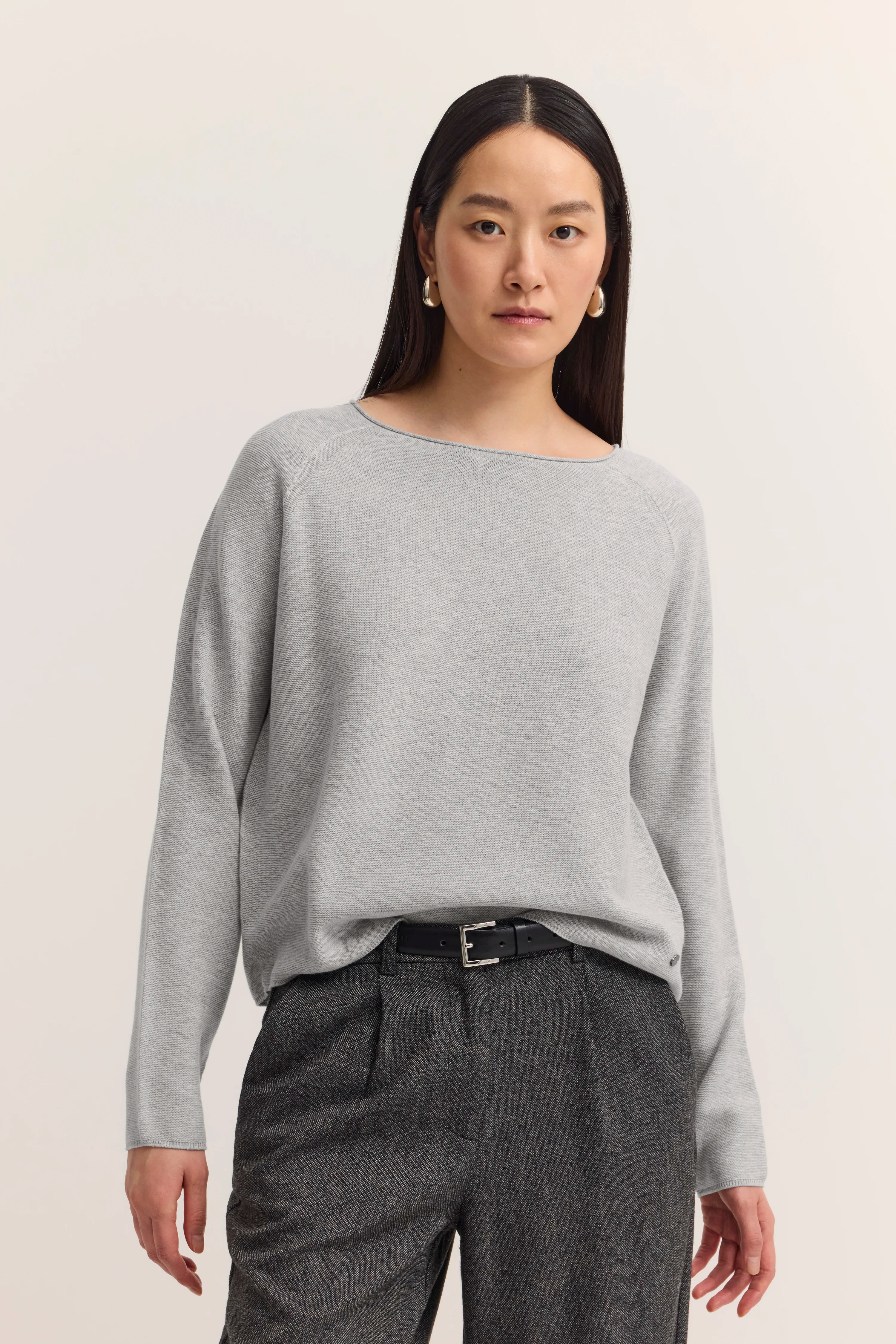 Grauer Pullover und graue Hose auf Modelbild, entspanntes Posing.