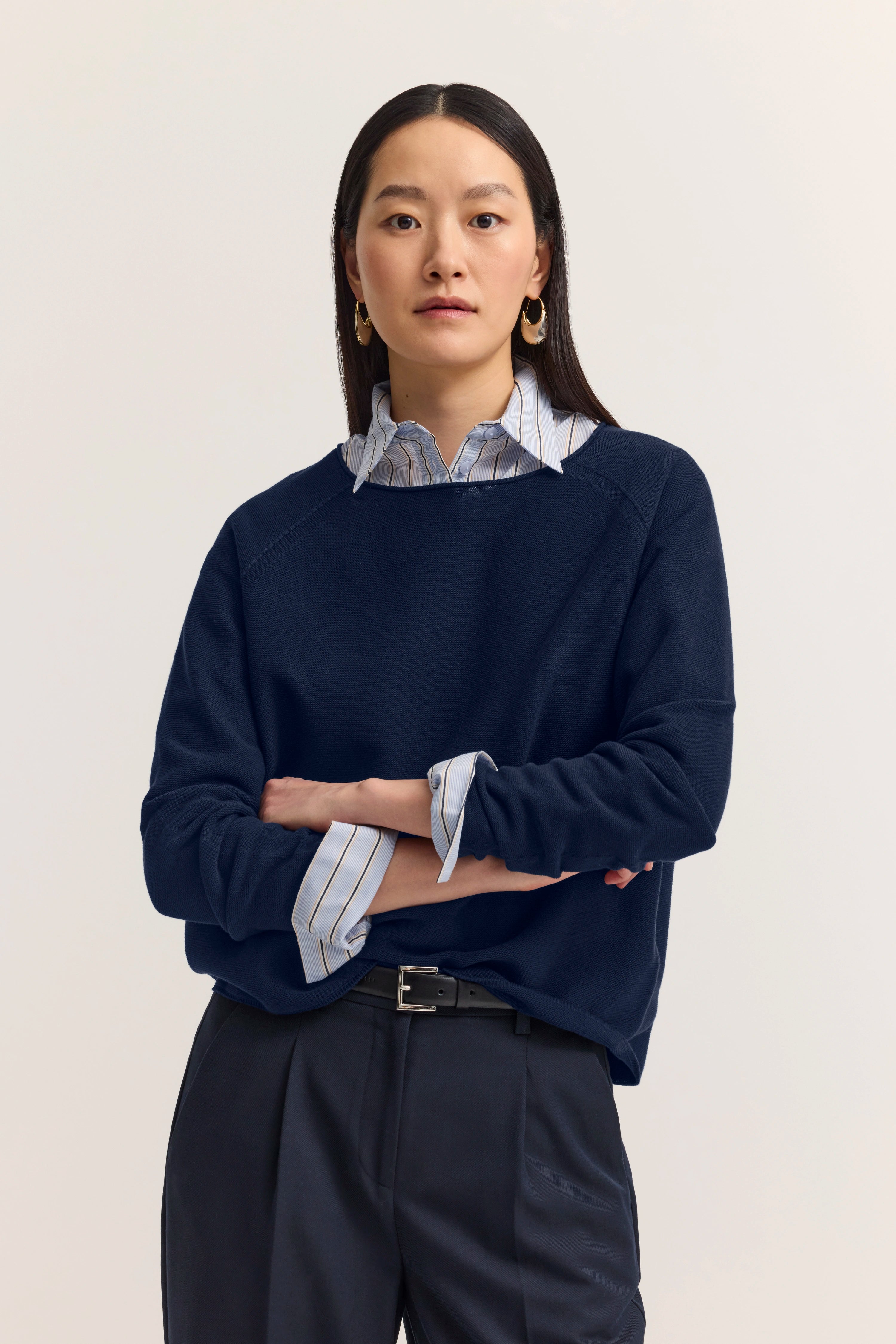 Model in navy Pullover, gestreiftes Hemd darunter, schwarze Hose