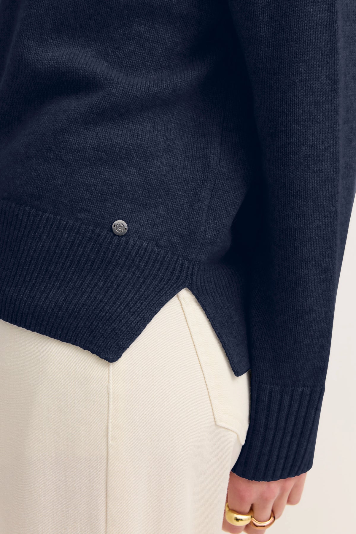 Dunkelblauer bugatti Pullover, cremefarbene Hose, Detailaufnahme, legerer Stil.