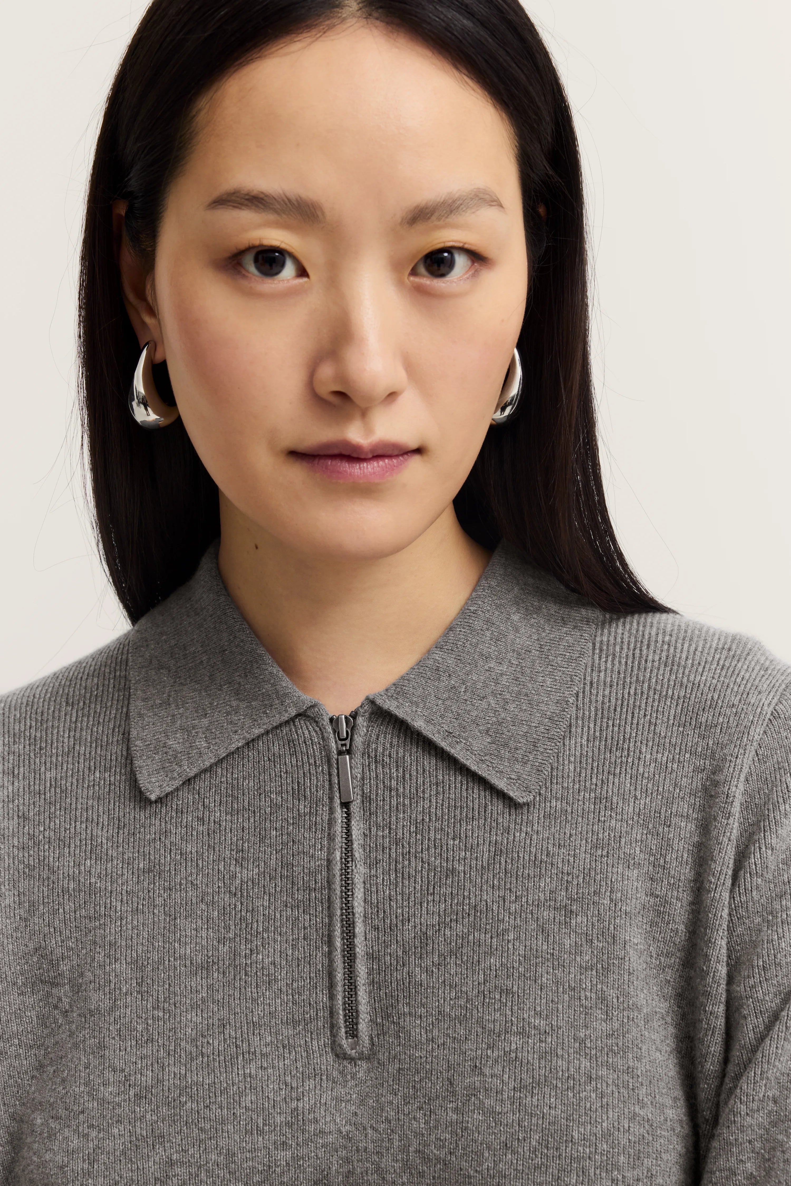 Grauer Strickpullover mit Reißverschluss und Kragen, Modelbild, Fokus auf Oberkörper, eleganter Look.