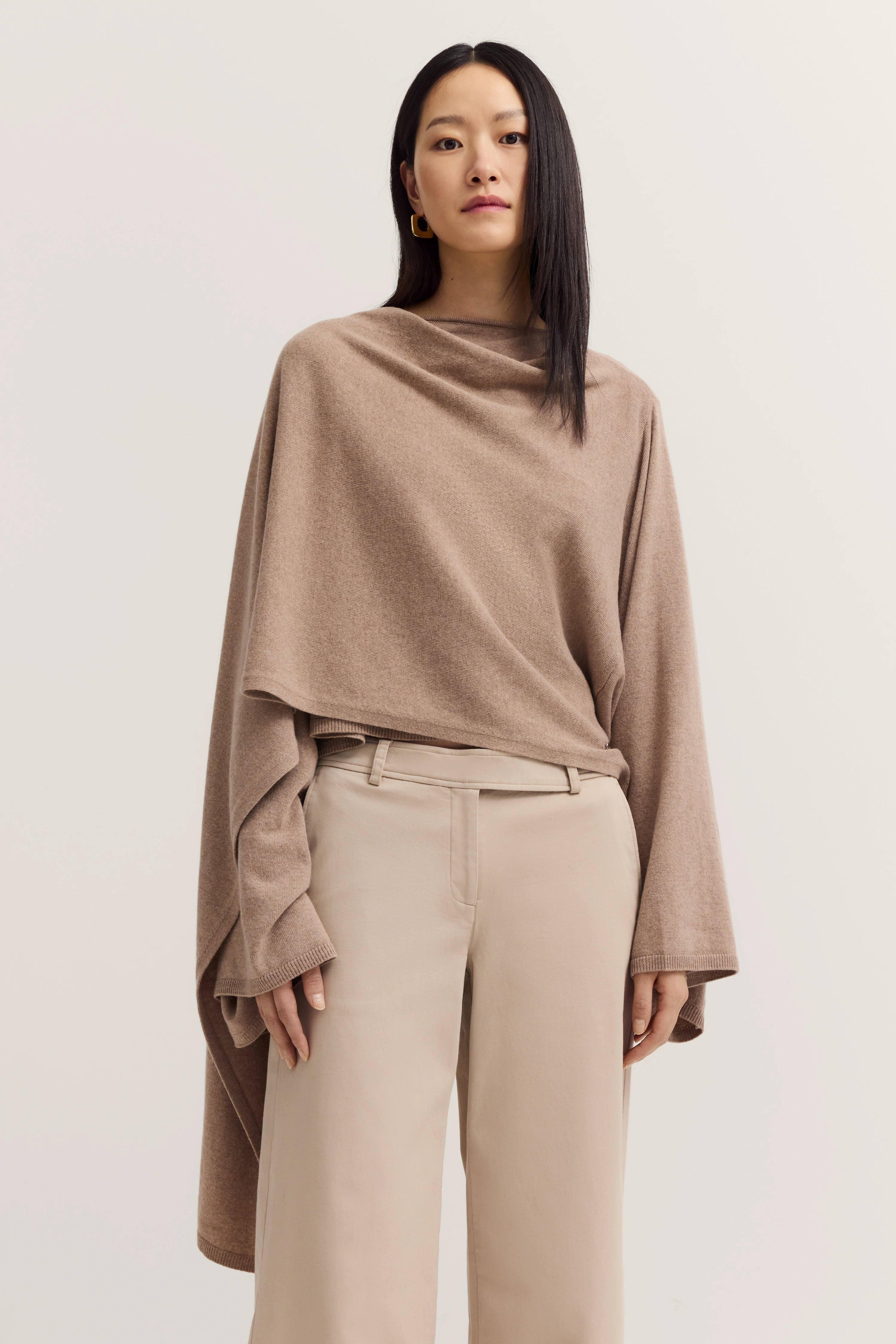 Modelbild: Frau in beigem Poncho und Hose, relaxed Pose.