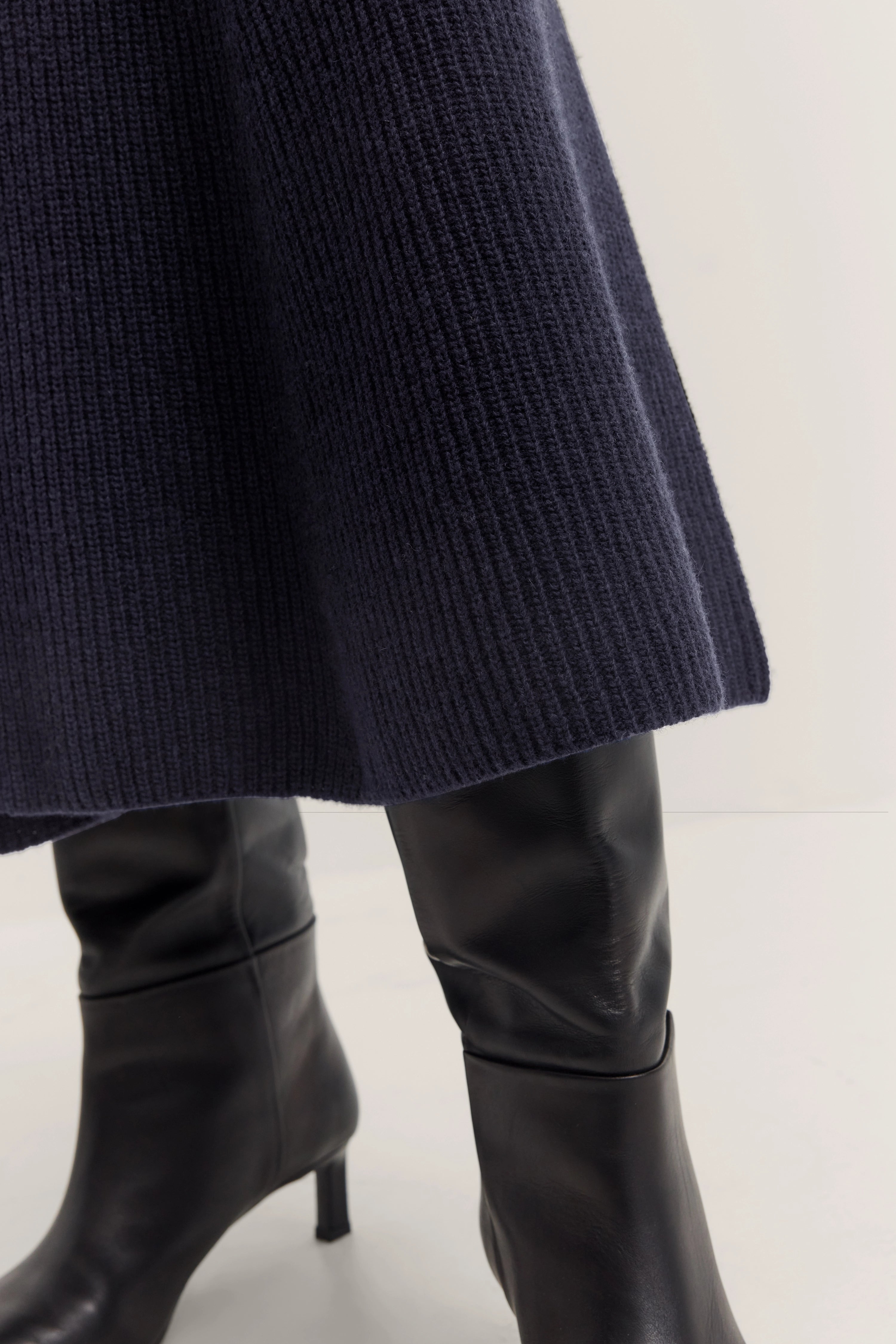 Donkerblauwe gebreide rok met zwarte laarzen, detailweergave, elegante stijl van bugatti.